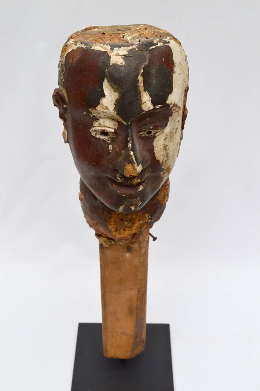 This is a most unusual sculptured head. Was it made for a mannequin or a huge puppet? A very unusual and special object displayed on a handmade metal stand.