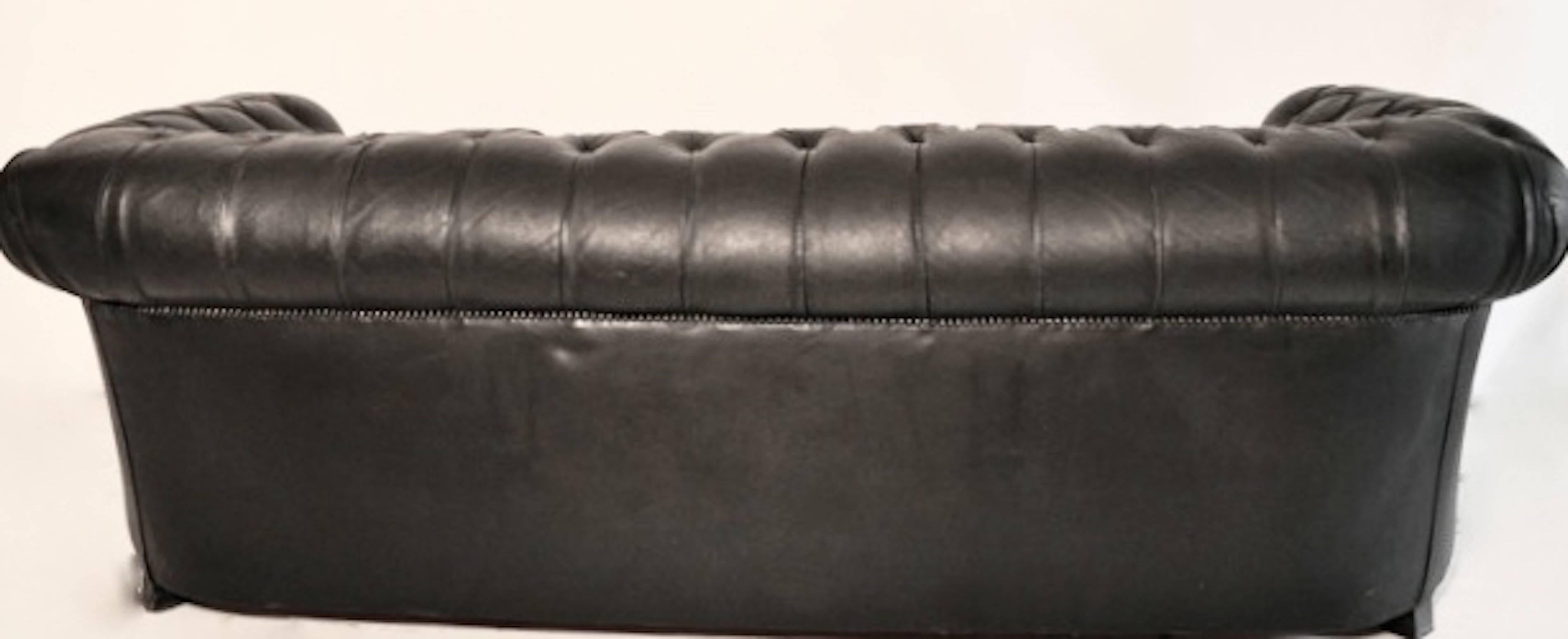 Beautiful vintage English chesterfield leather sofa, circa 1950. Well tailored details such as the pleated arms and the covered feet lend an extra touch of luxury. The leather has acquired an elegant patina but still remains in good condition.