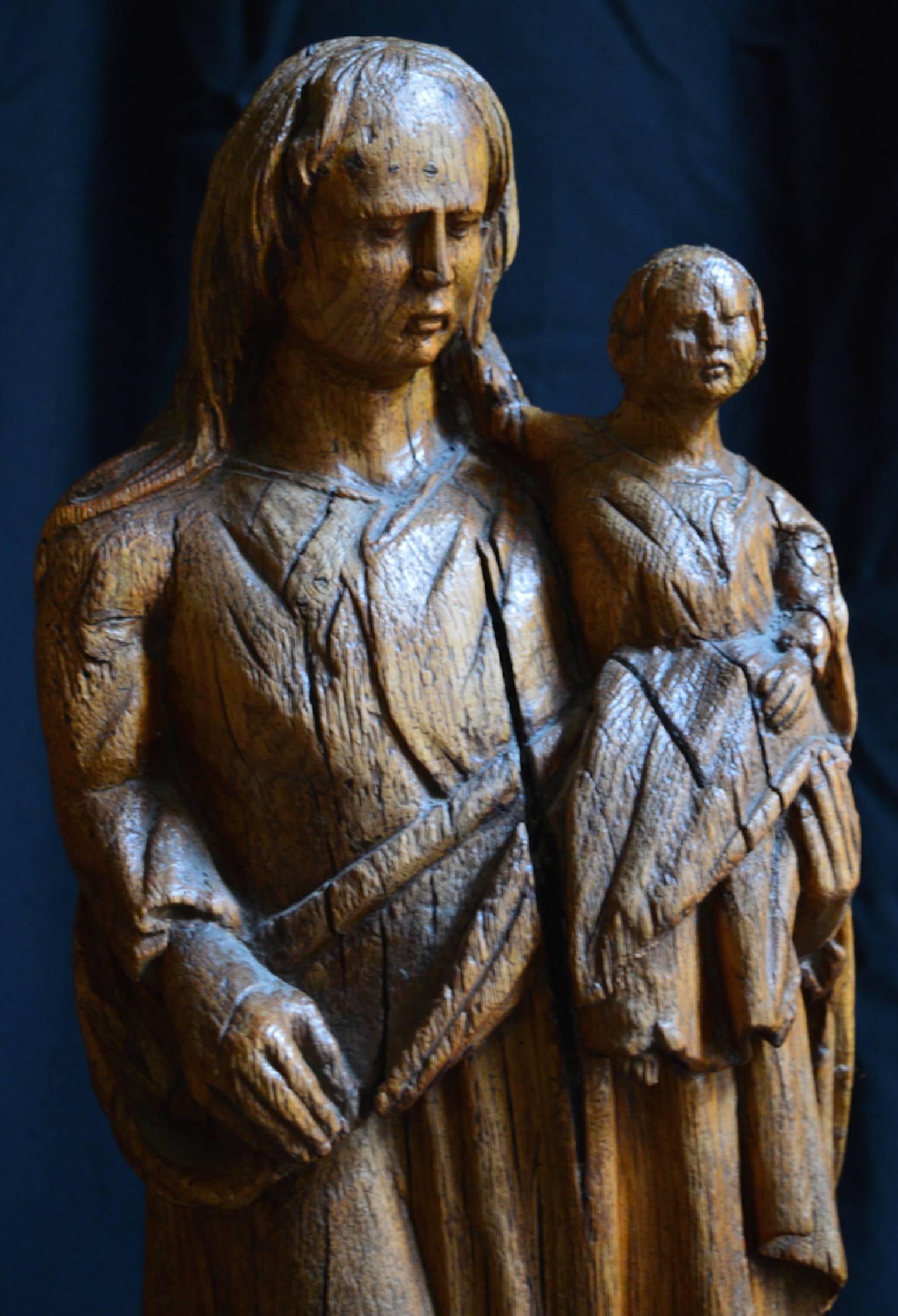 A charmingly naive 18th century carved oak statue of the Madonna and Child. This is a statue that was carved by a country person as a devotional figure to be used in his home; note the wear to the feet and heads as they were traditionally rubbed