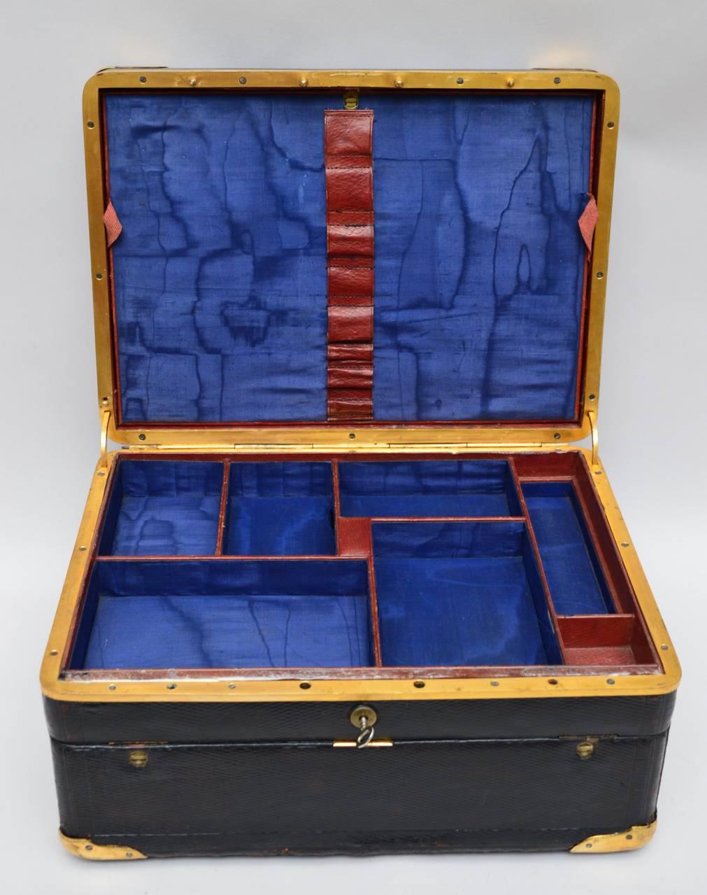 A French travel box, circa 1900. Many royal blue silk lined compartments to hold cufflinks, watches and writing accessories. The interior of the lid opens to reveal a stepped leather envelope to hold stationary and documents. The front of the box