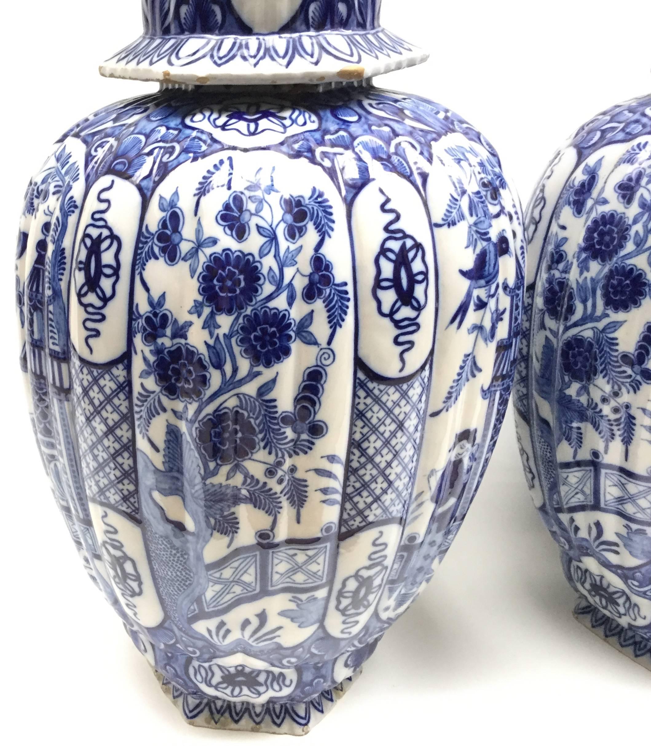 A monumental pair of delft blue and white baluster vases with garden scenes in the chinoiserie style. Whimsical cat finials top the hexagon lids.
In beautiful presentable condition with some chips and repairs that are to be expected in soft bodied