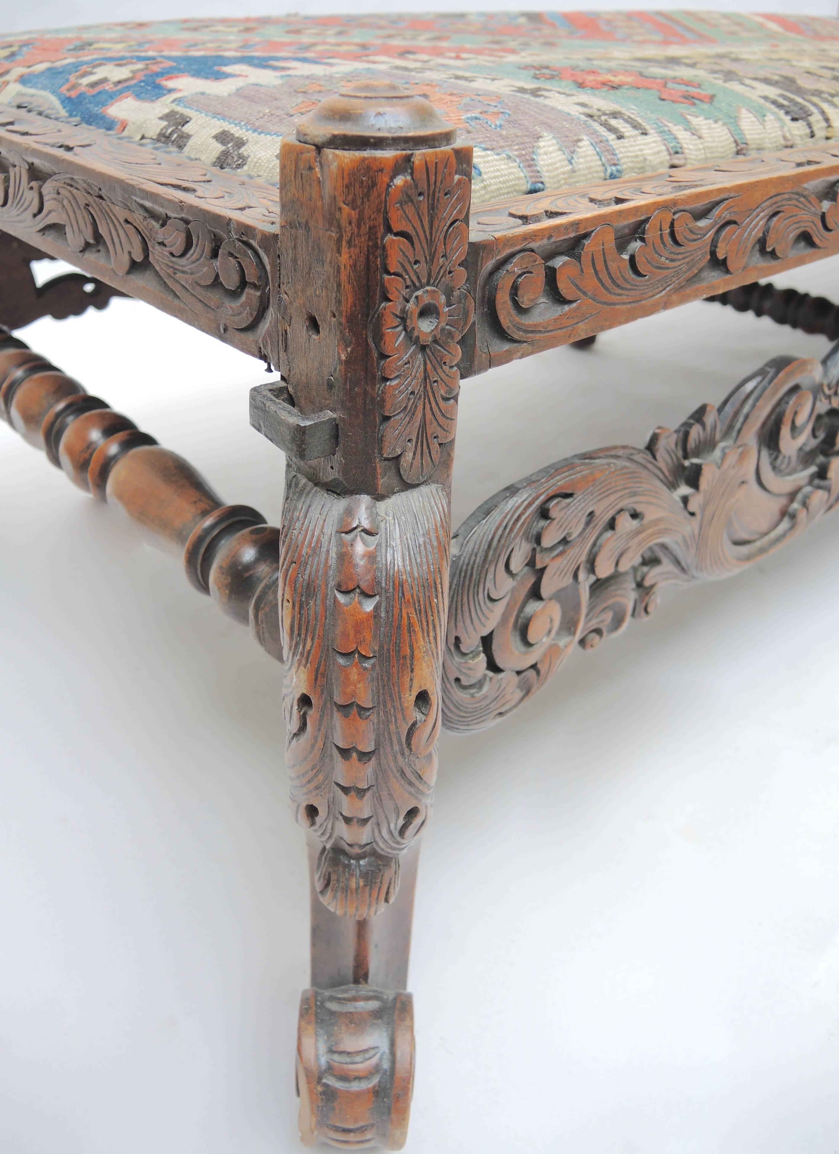 17th century Dutch Baroque carved oak bench upholstered in antique Kilim carpet and finished appropriately in brass nails. Originally used with a removable cane woven back (hand-wrought iron holders remain) this bench is the perfect height to use at