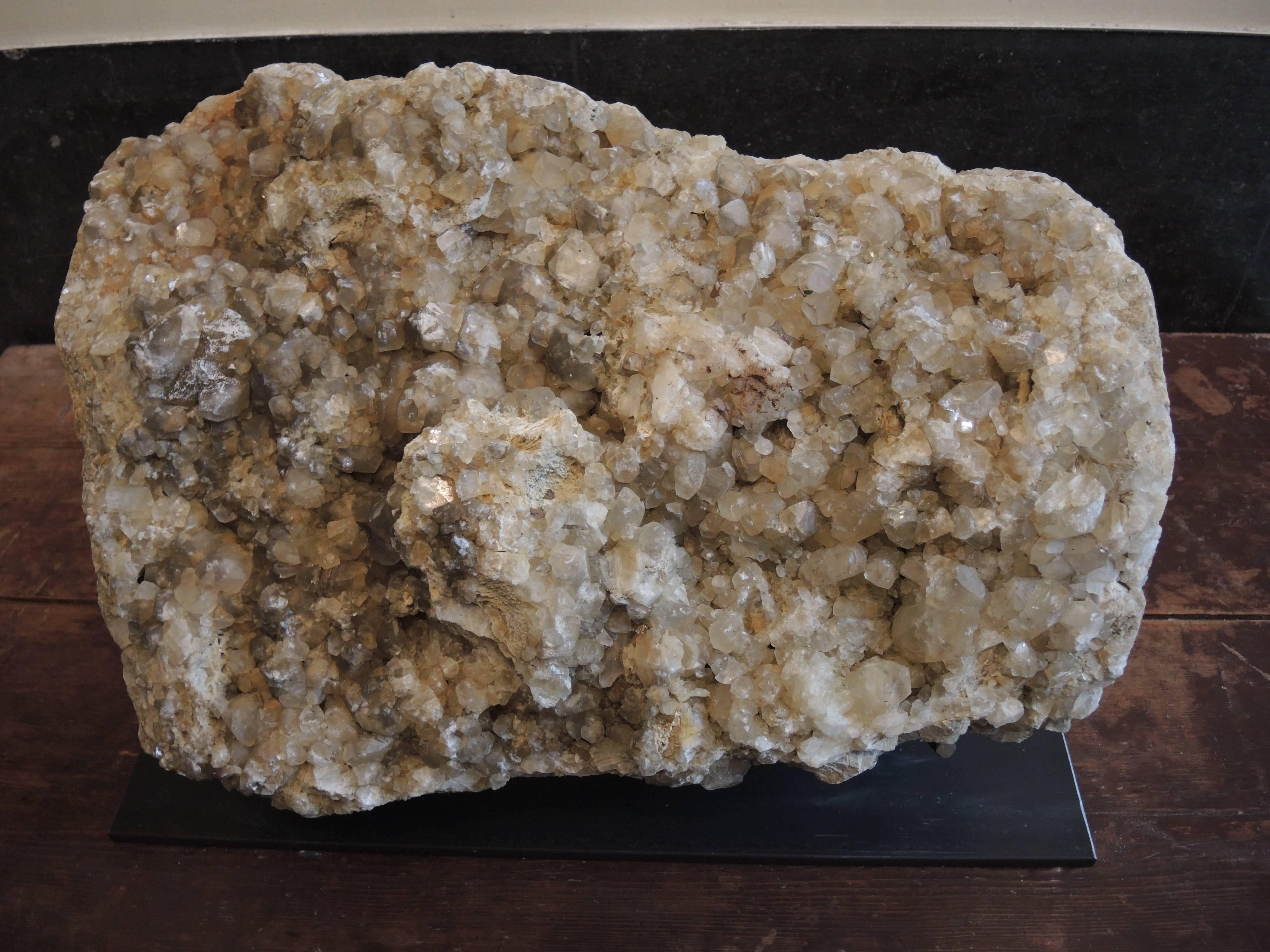 A large quartz crystal geode stone on a custom-made metal stand.