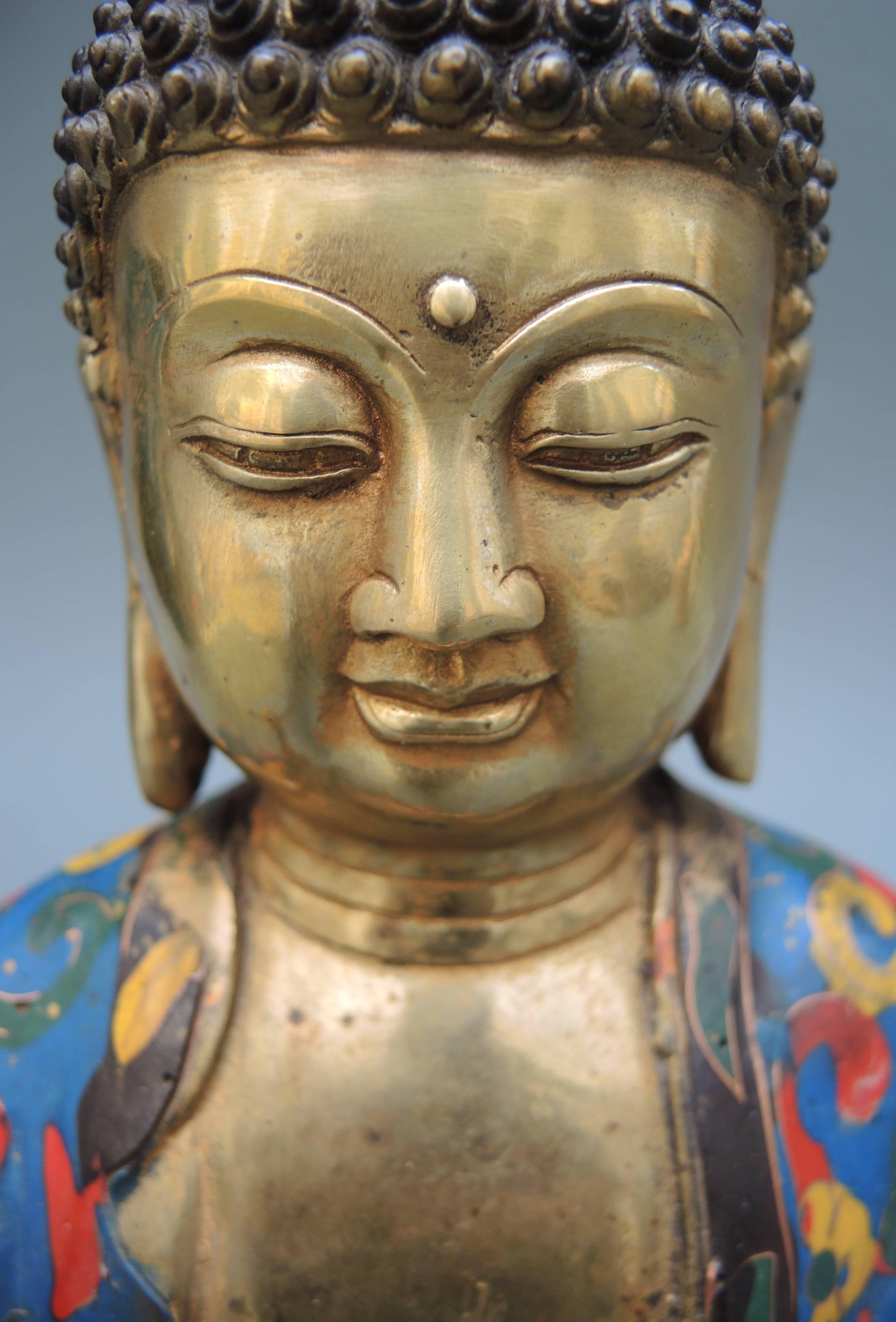 A beautiful and serene gilt bronze Buddha statue of Shakyamuni Tathagata Buddha. An unusual combination of classical bronze with a more modern feeling application of abstract cloisonné enamel work.
Buddhism, the religion and philosophy developed
