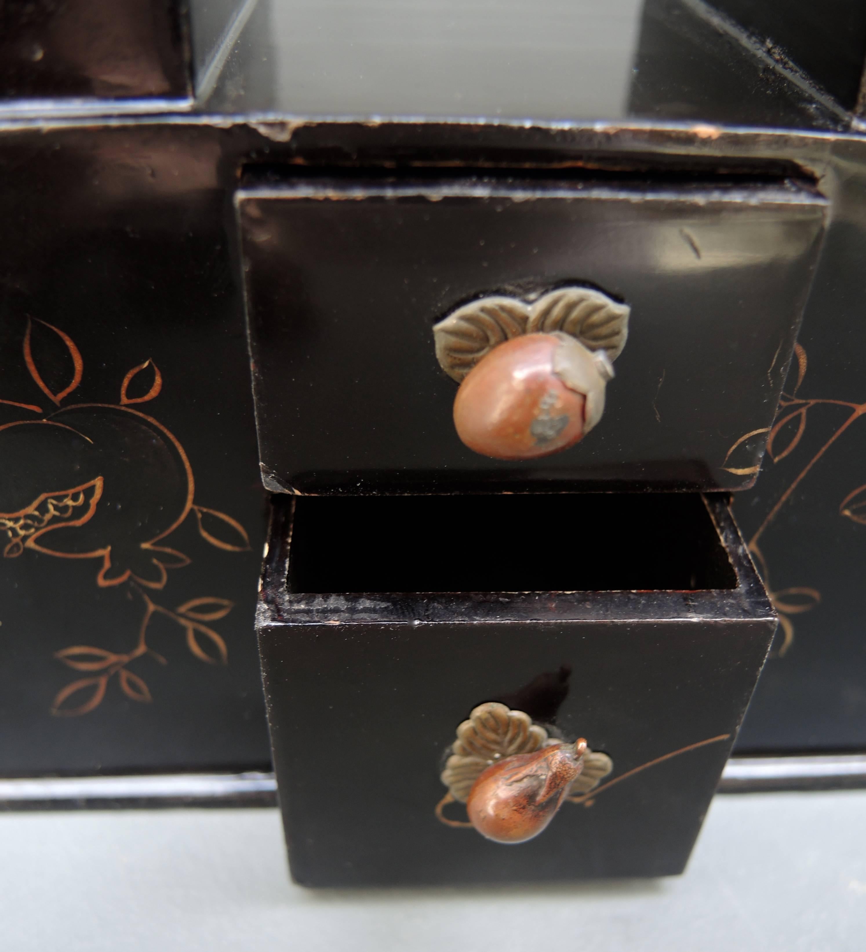 19th century lacquered card box with two drawers for dice or game pieces.
The drawer handles are finely cast in bronze and depict a persimmon and an eggplant. The depiction of the persimmon used in combination with other objects is to give good