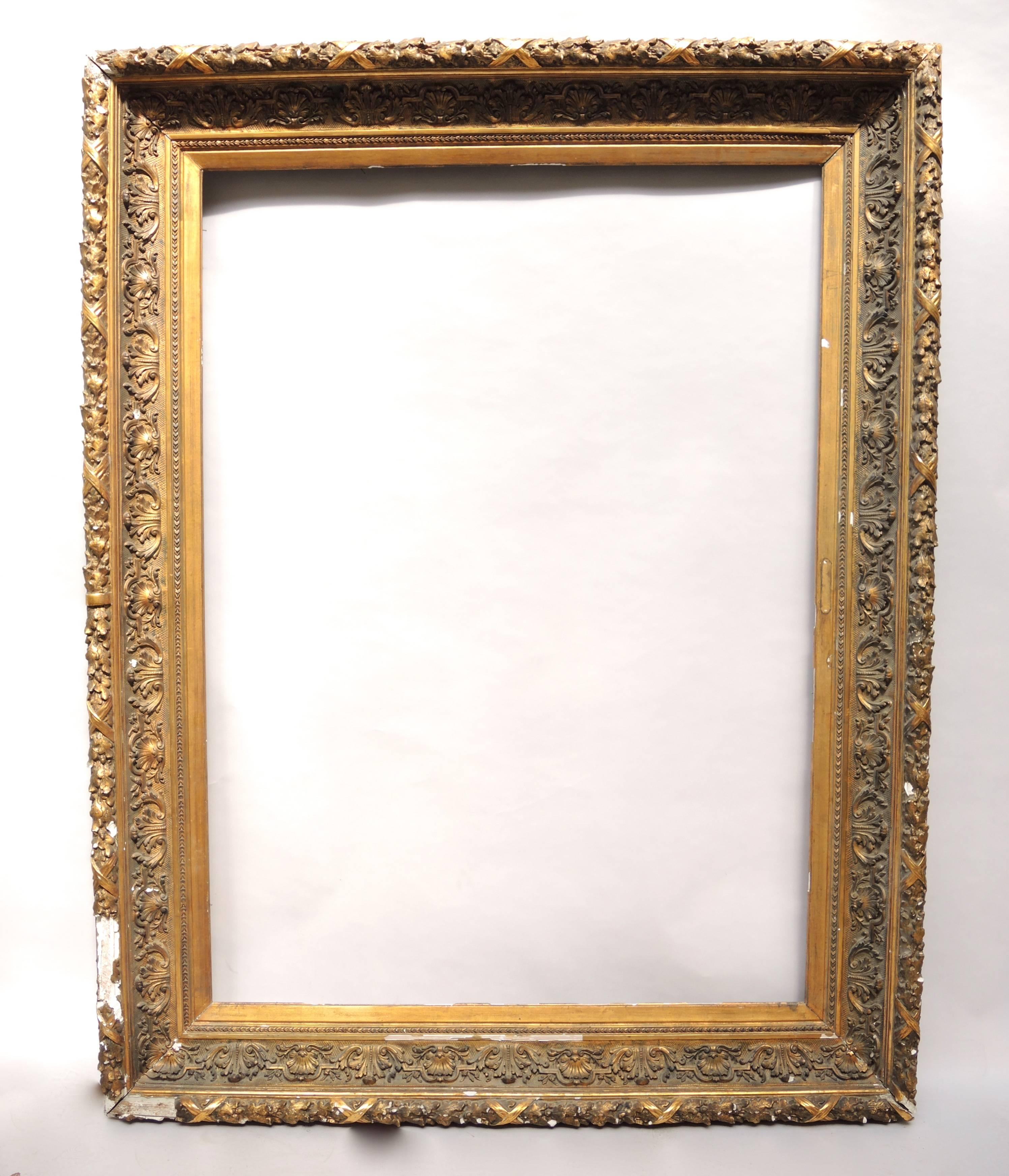 This huge 19th century painting frame is the epitome of old world chic with its detailed design and age worn surface. The heavy wood frame is adorned on the outer edge with gilt gesso garlands of oak leaves with acorns and on the inner edge with