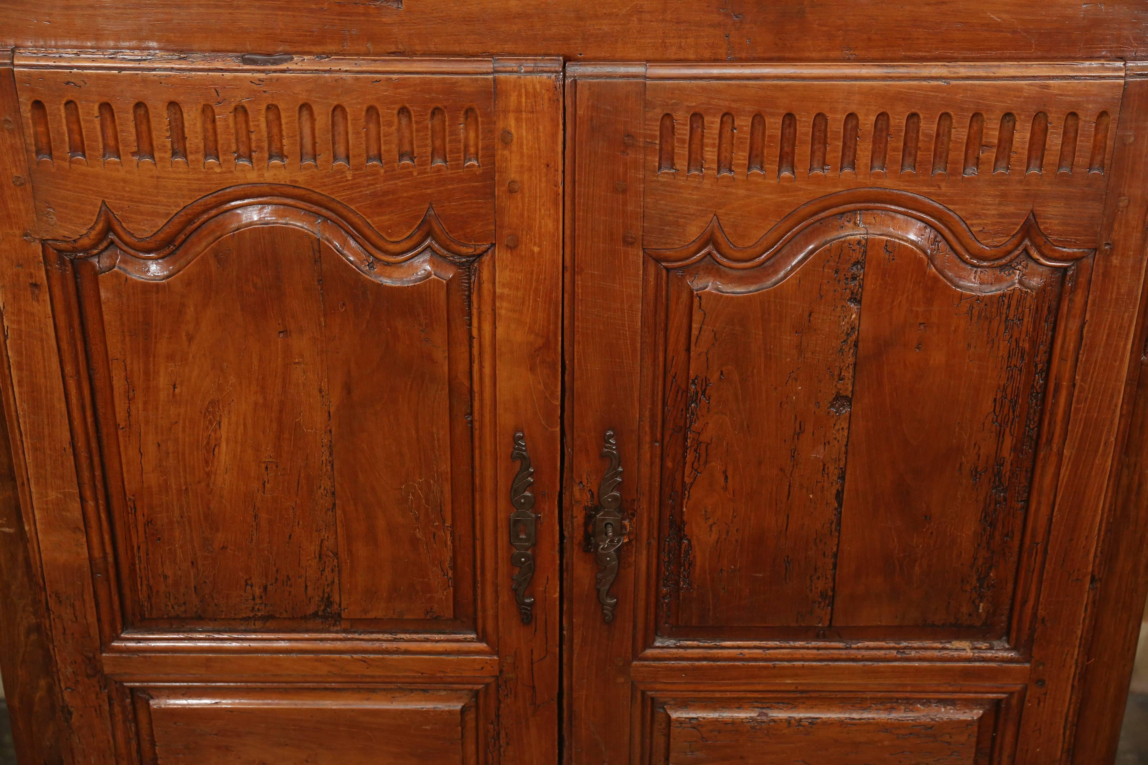 Carved chestnut cabinet has block-panel doors with a curved top panel over which has fluting and below another framed panel.

The cabinet has a curvy cut apron, in front.

Behind doors are two shelves for storage.

Sides are block panelled and