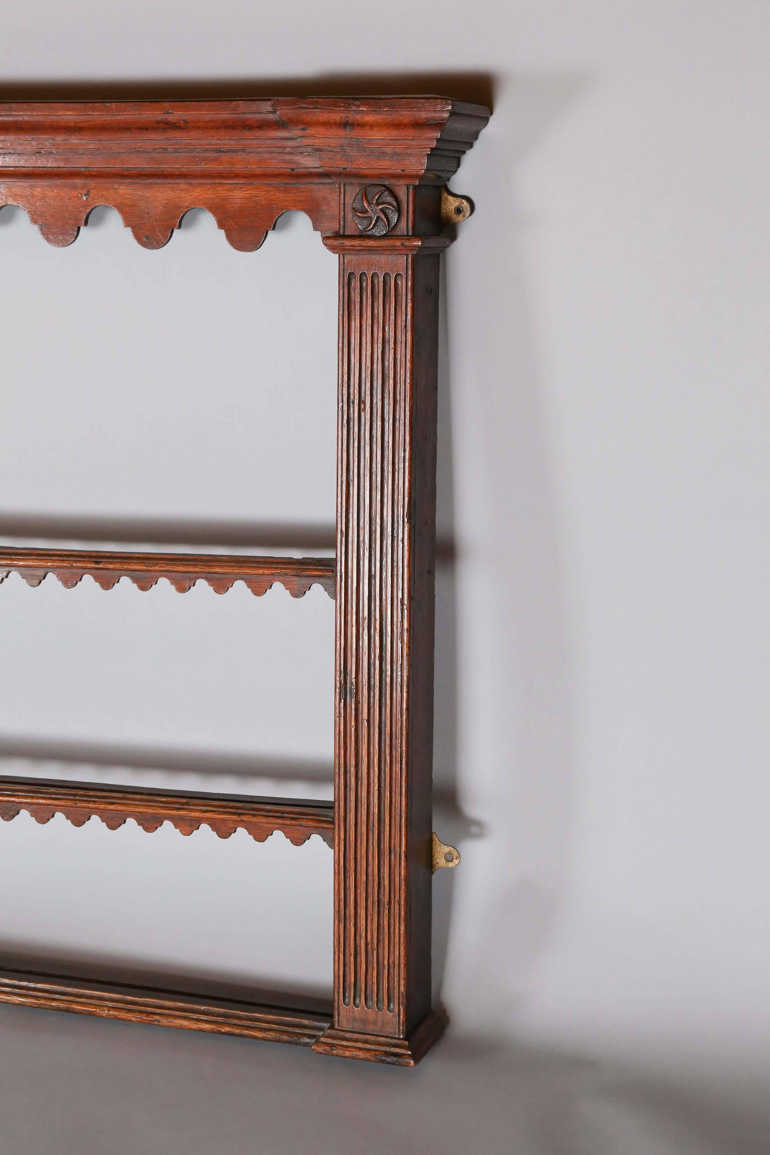 George III period oak plate rack with wonderful scalloped detail, applied carved roundels above fluted pilasters on each end.