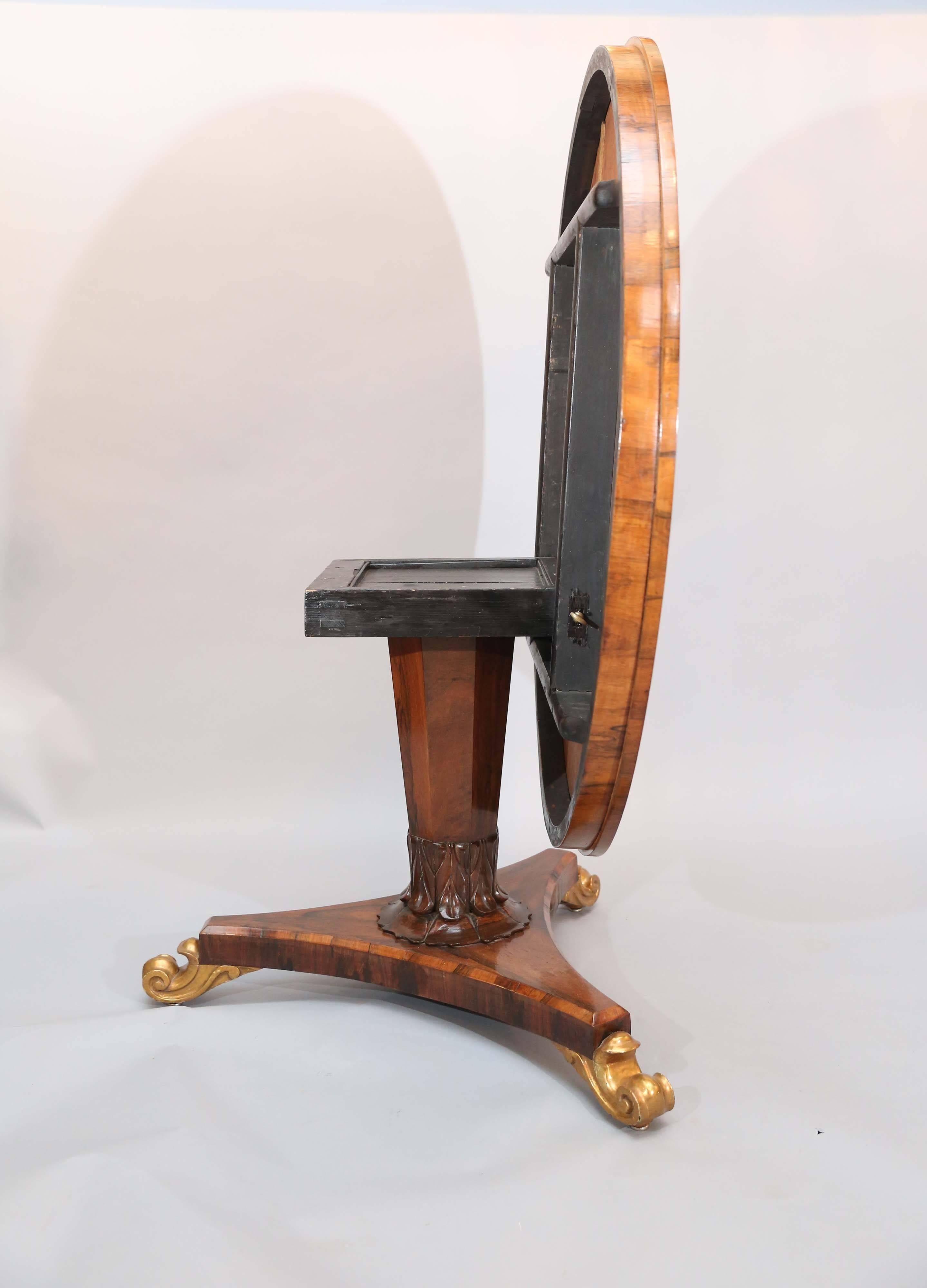 This extremely handsome rosewood tilt-top table has a nice thick apron
of crossbanding.

Pedestal is faceted with decorative carving where sits on triangular base, again with crossbanding and rest on three carved and gilded feet.

           