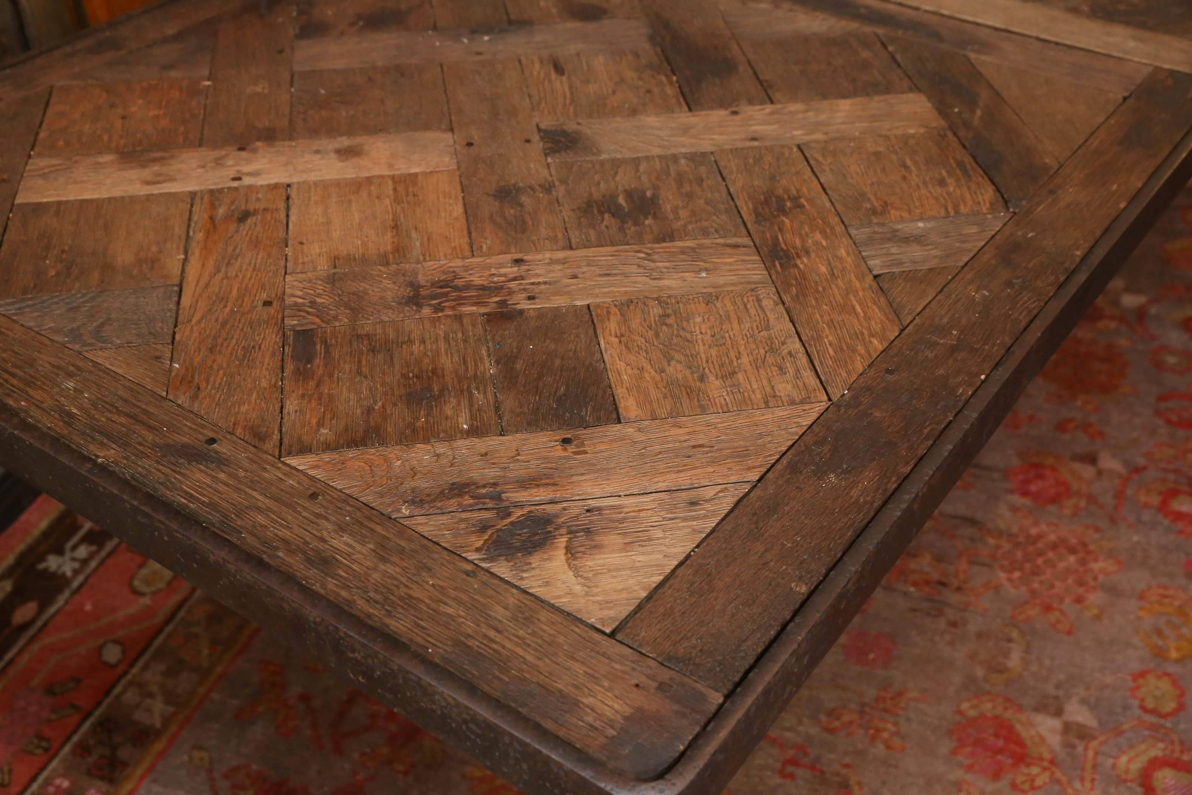 Des Versailes oak parquet top in set in a wrought metal frame and sits on
two 1940s metal bases with bun feet and connected by a center brace.

Very Rustic looking and quite unique.

