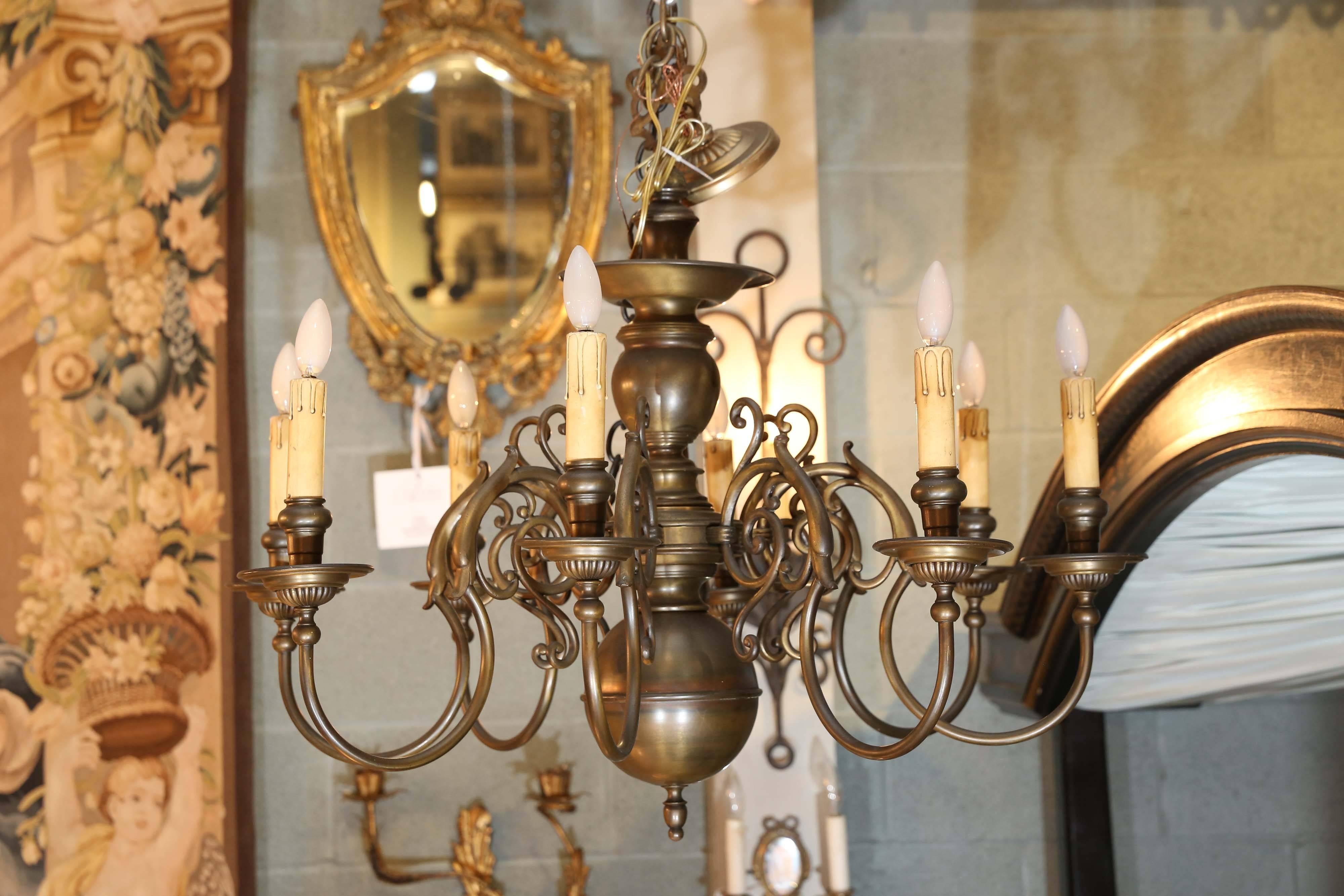 Brass chandelier has lovely spiraling arms and very handsomely detailed fluted bobeches and candleholders.

A finial is featured at the bottom.