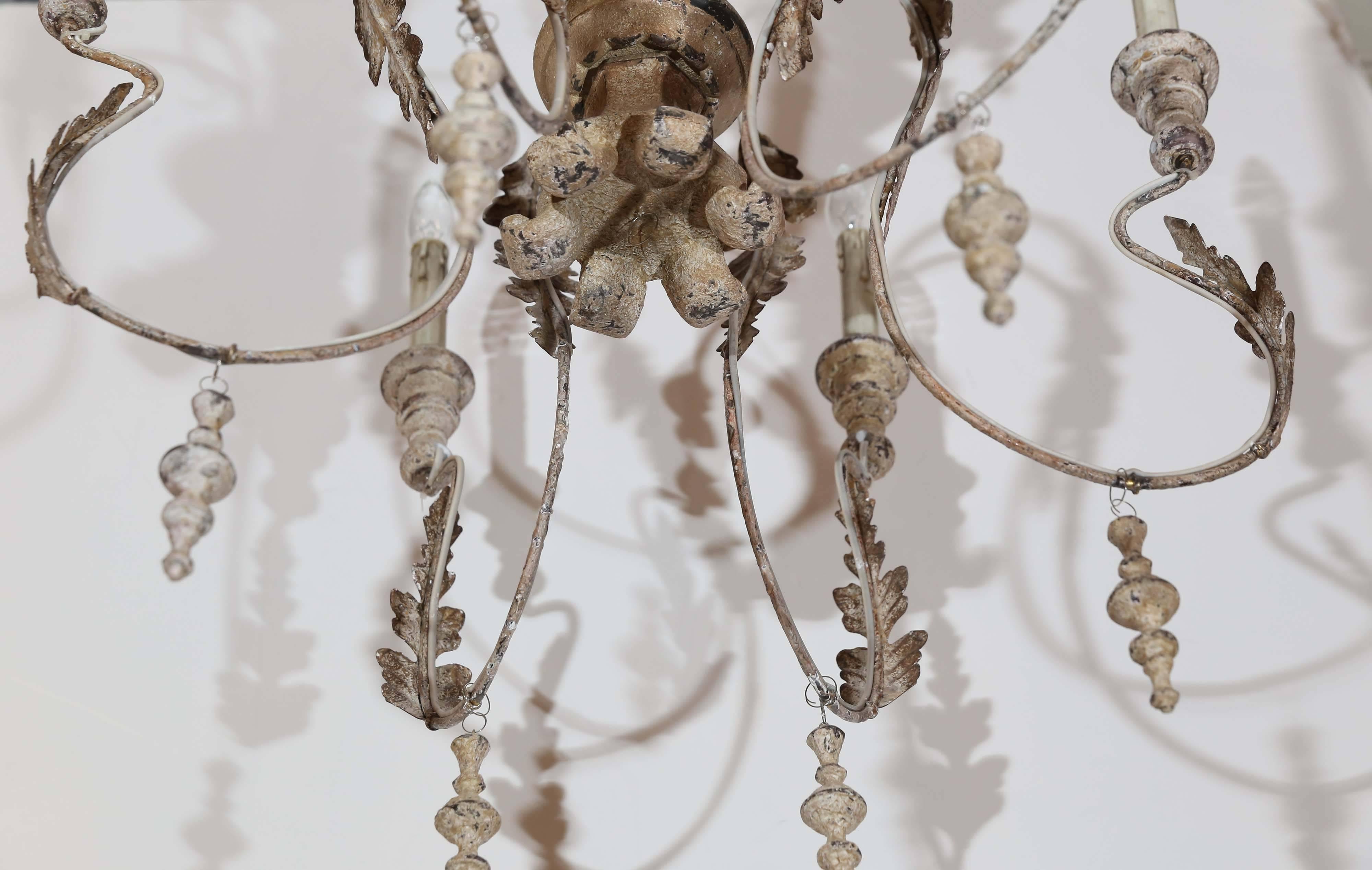 Chandelier is made up of turned wood with wire arms.

Details include metal acanthus leaves on arms and wooden tassels hanging from bottom.