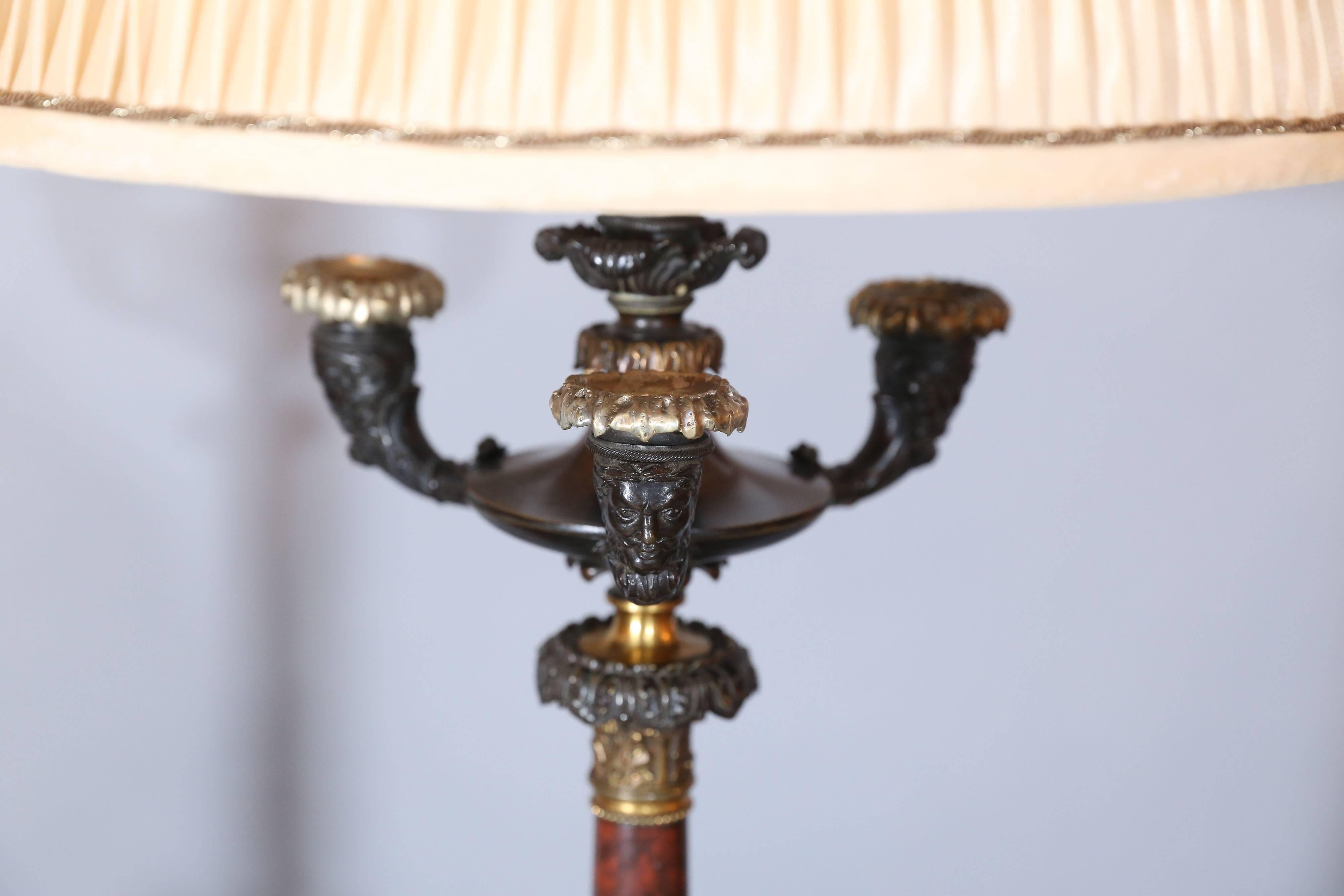 Tall pair of Regency four-light bronze repousse and marble candelabra with three mask head arms, above a marble standard.

Each arm holds a bobeche.

Center arm is wired leaving three-arm for candles.

Base is a two-part tripod with sleeve for