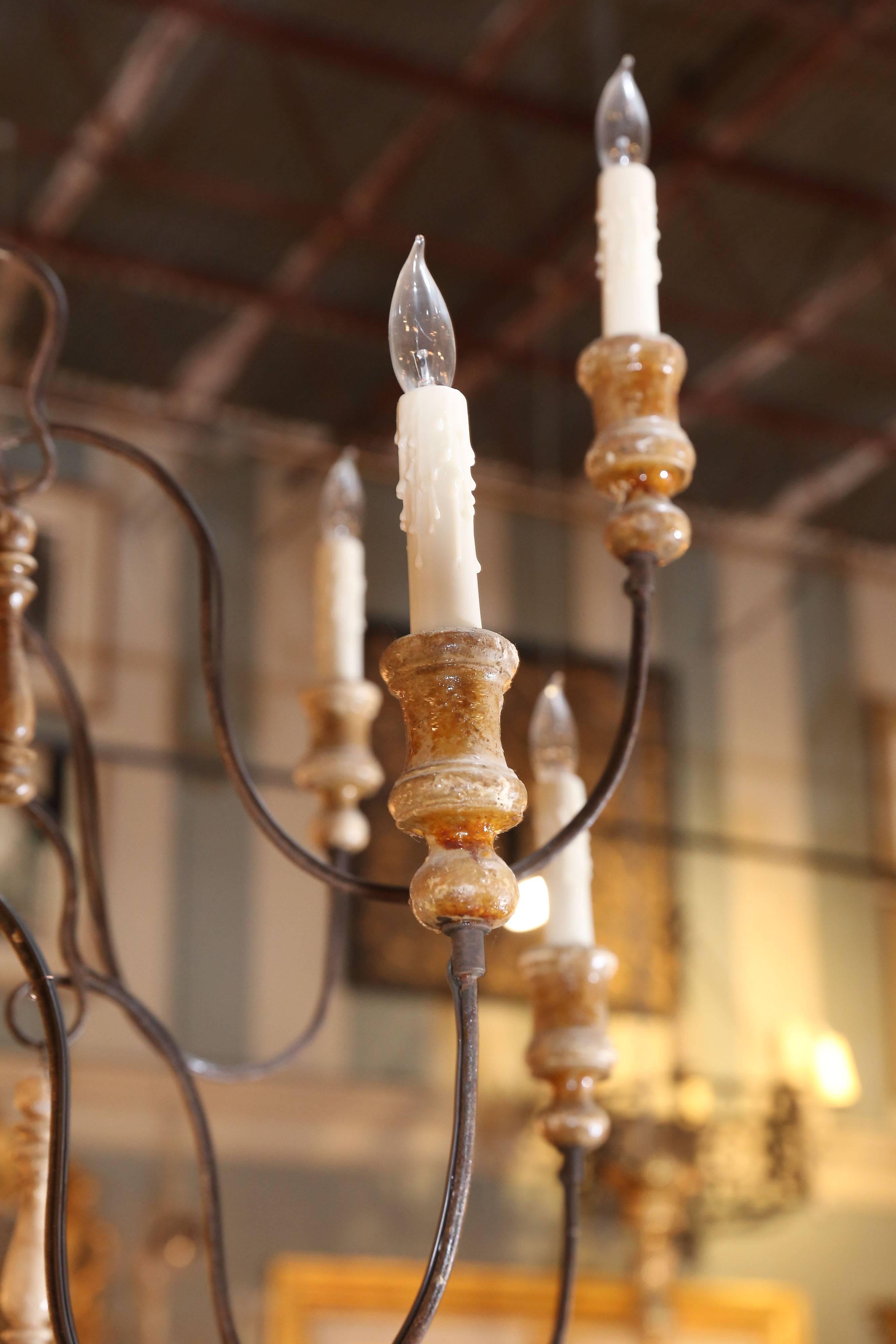 Large white-washed Swedish chandelier with carved candleholders, tassels and center pole.

There are two decorative metal pieces of trim dividing the center pole.

Chandelier arms are metal with wooden beads.
