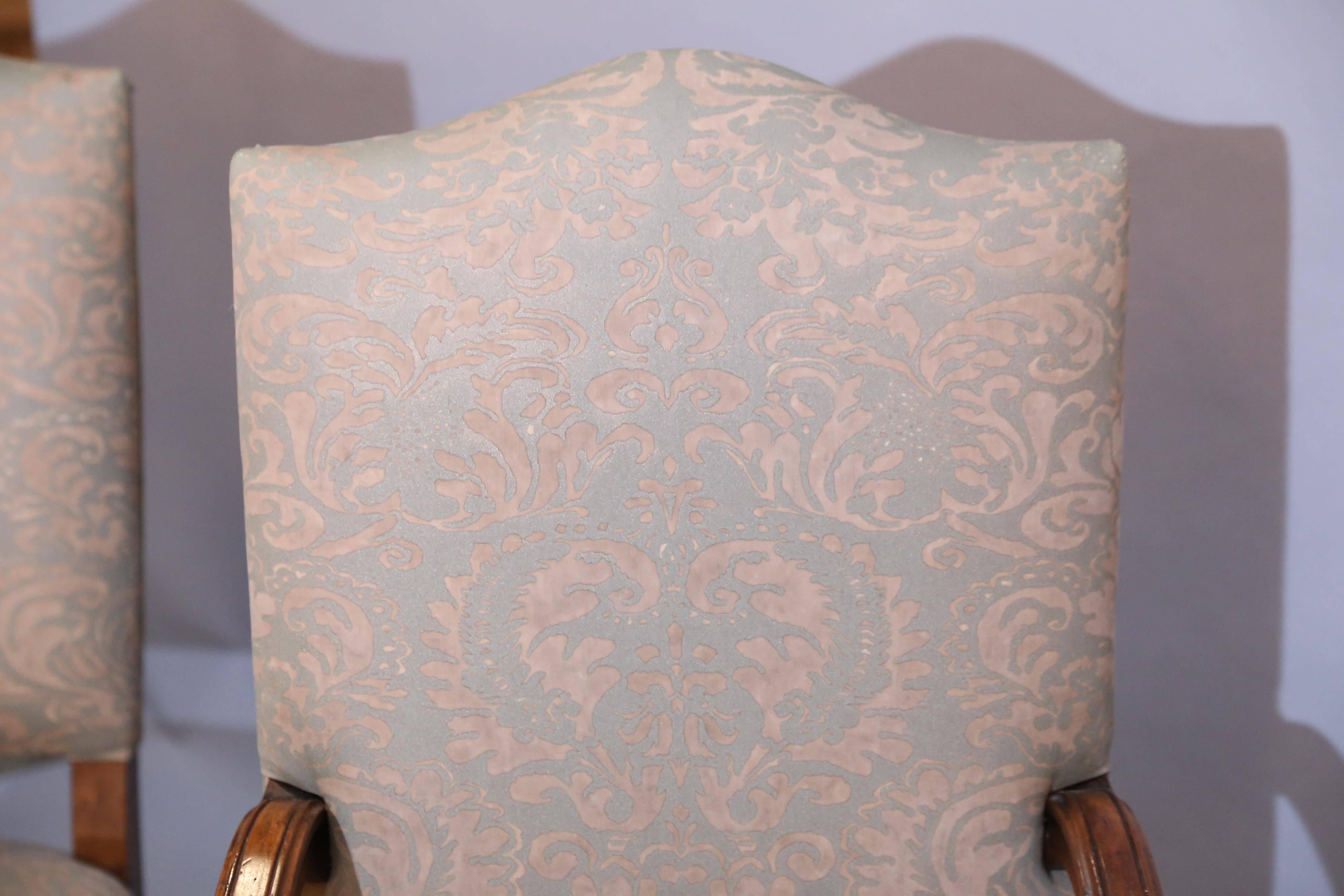Set of eight walnut French dining chairs, upholstered in a peach and silver Fortuny fabric.

The back of chair is shaped, the front legs and stretchers are turned.
Back legs are straight.


