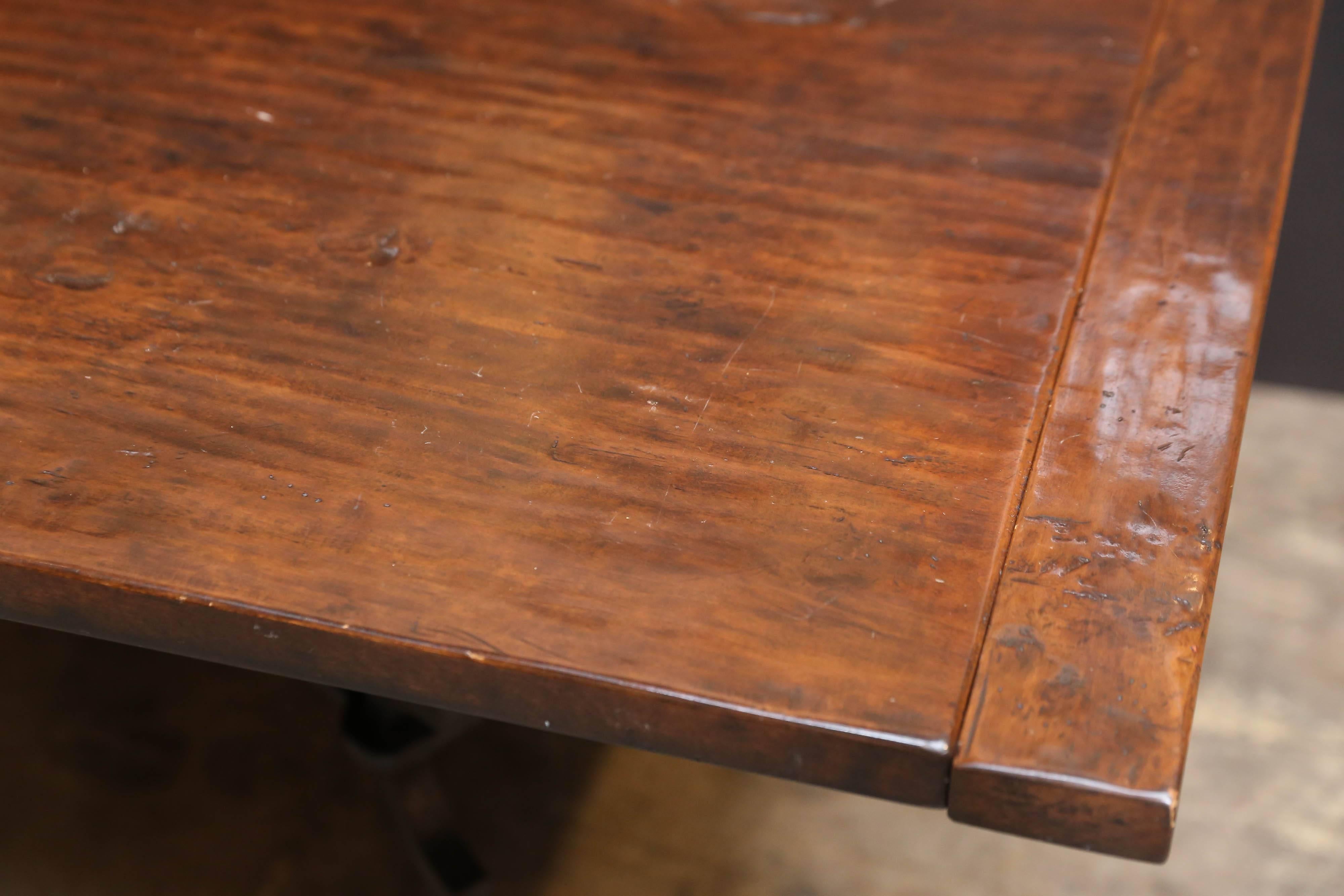 Walnut refectory table with hand-hewn look on top and elaborate black wrought iron
Base.
Surface blemishes to look old. 
18' table leaves that fit on each end. Protected in felt bags.
 