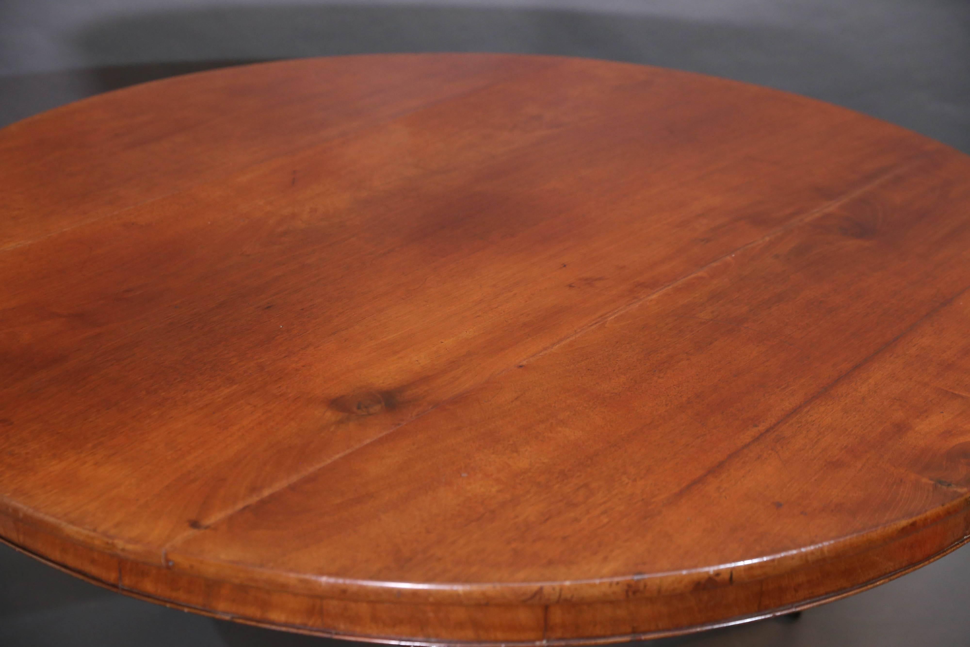 Period English Regency round tilt-top table with solid mahogany top and 
 Circular pedestal base resting on three legs on brass casters.

Apron is 3