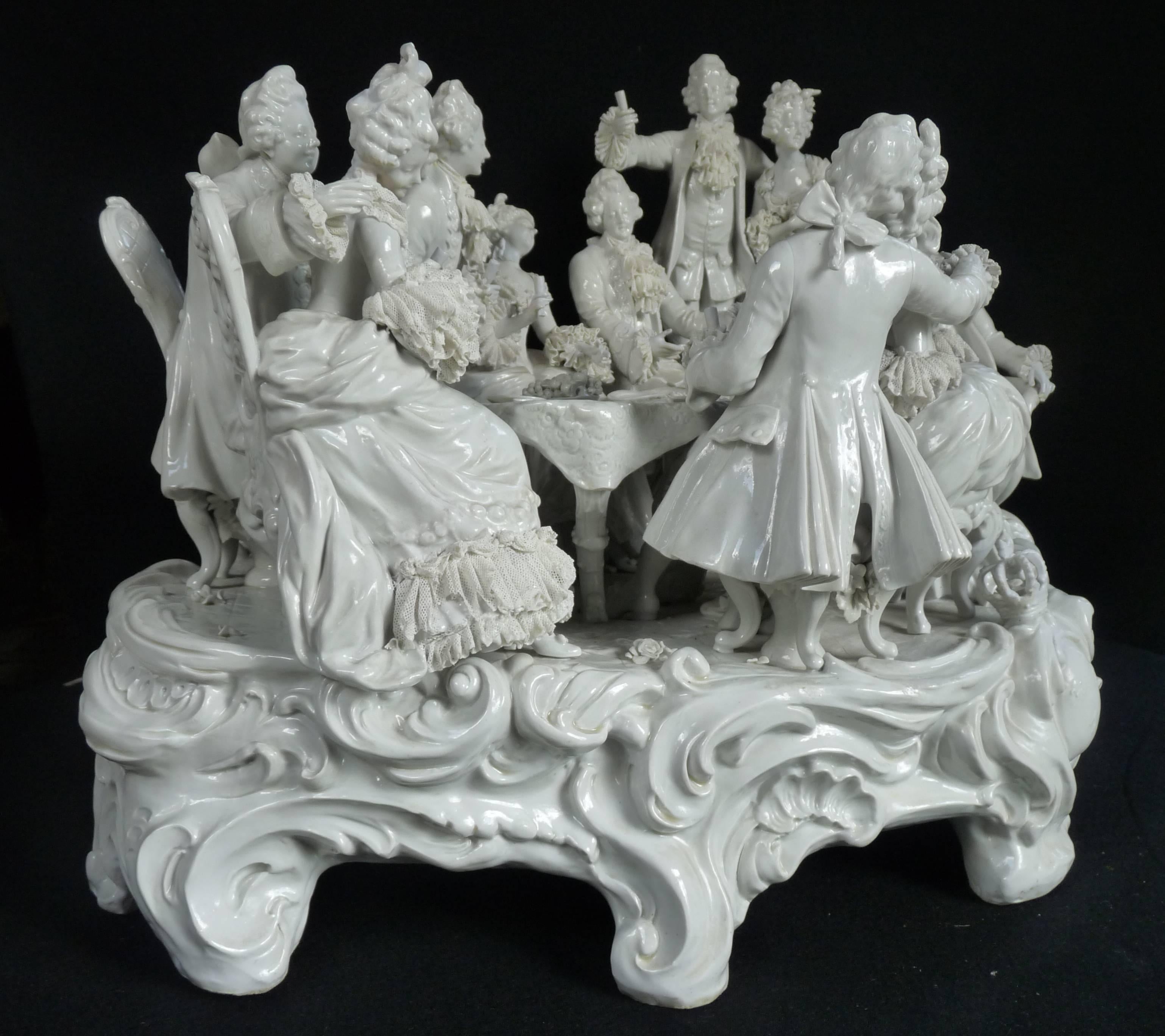 Blanc de Chine porcelain figural group of 18th century revelers around a banquet table. 
Porcelain bears the underglaze blue maker's mark of th Oldest Volkstedt factory, of Thuringia, Germany, 1760.

There are some factory-made repairs...On large