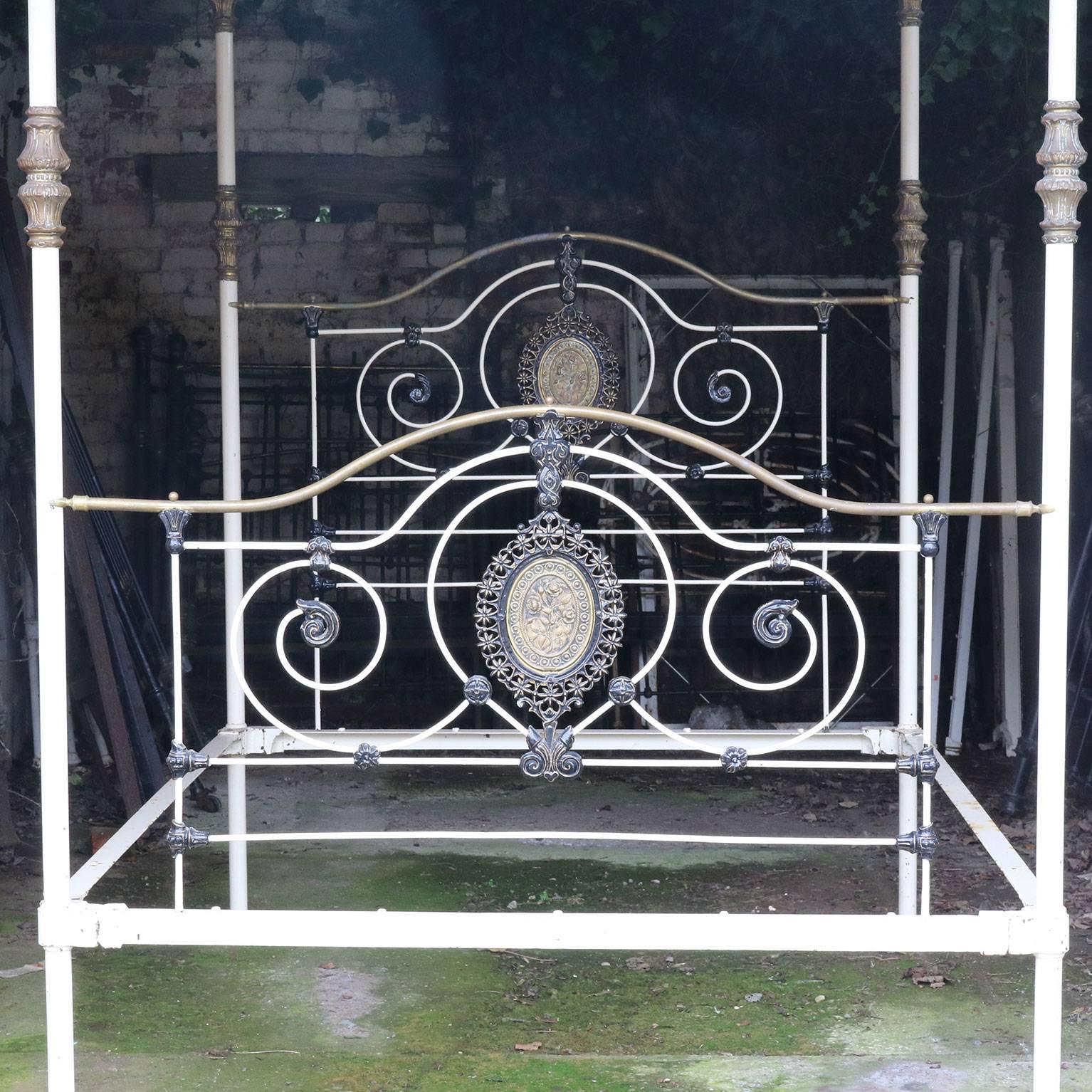A cast iron and brass four-poster bed from the mid-Victorian era with Fine cast iron work and central brass plaques, serpentine brass top rails and decorative brass fittings.

This bed has been hand-painted white over black metal with the castings