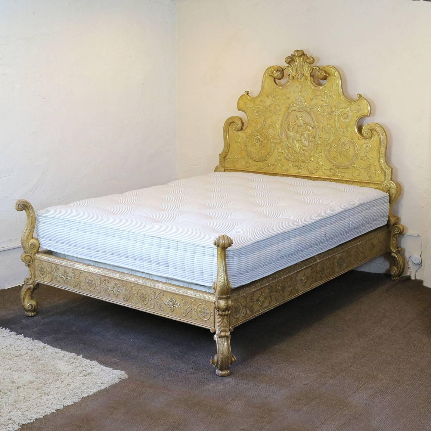 A fabulous gilded bed with tall back panel and torchon feet. The bed has been decorated with ornate gesso work depicting a scene of mermaids, three feathered pediment, eagles' heads and scroll work.

This bed accepts a British king-size or