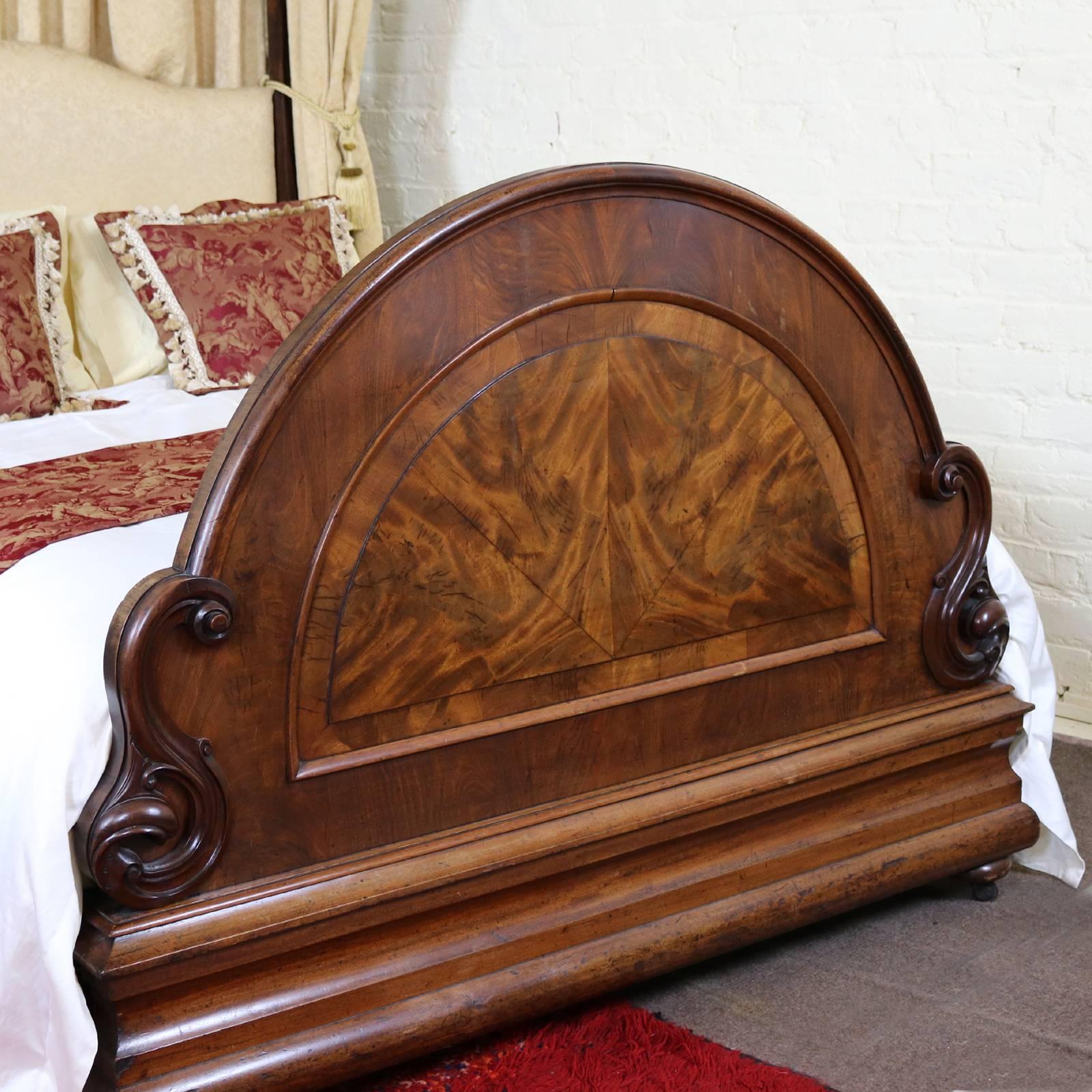 A magnificent Victorian bedstead with flame mahogany arched foot board and shaped canopy. 
The side runners and the back posts have been replaced and the arched back board has been upholstered in the same fabric as the drapes, which are included in