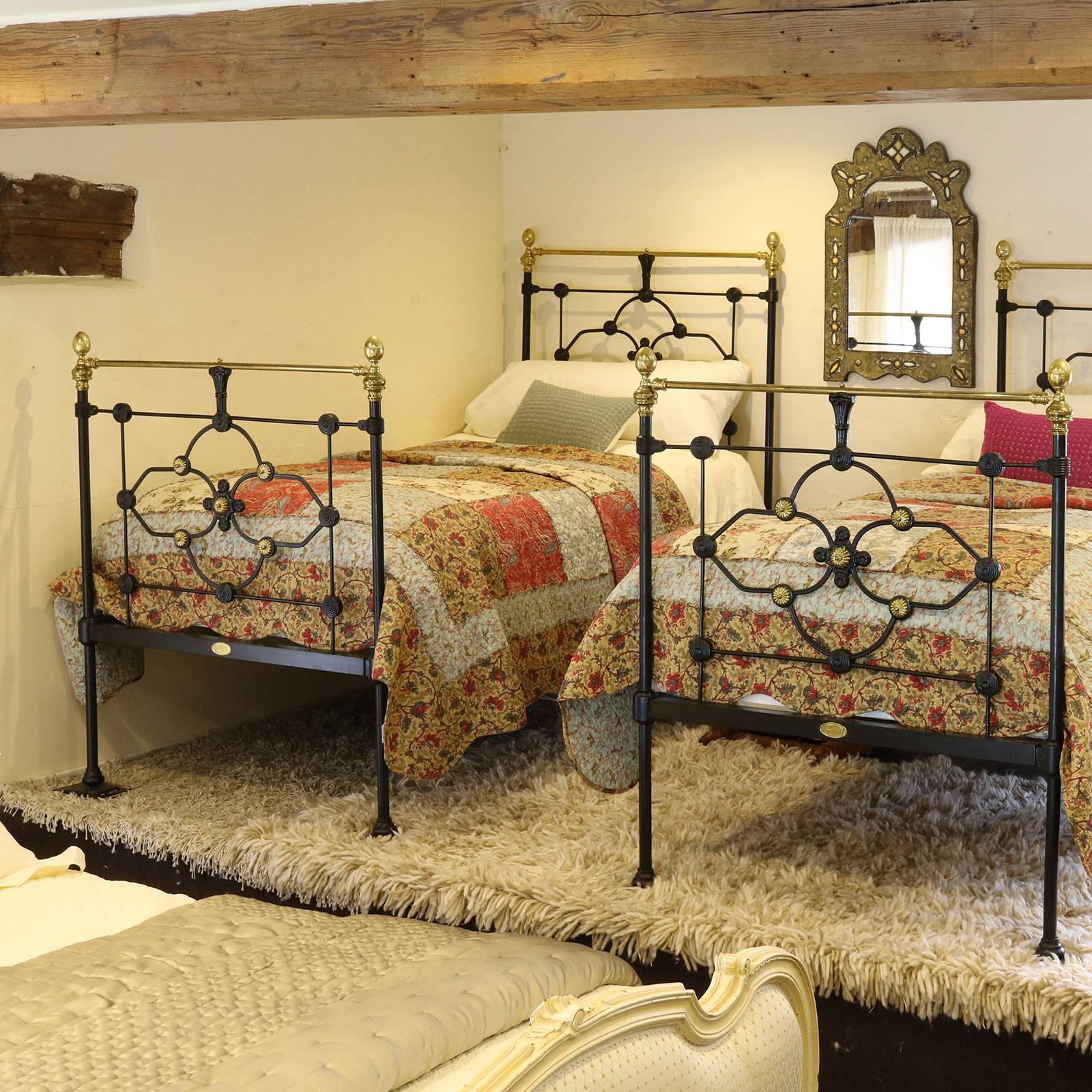 A fine matching pair of cast iron and brass beds finished in black with brass rosettes, brass top rails and brass finials.

These beds accept standard single size, 3'0 wide (36 in or 90cm), bases and mattresses. The current length of mattresses