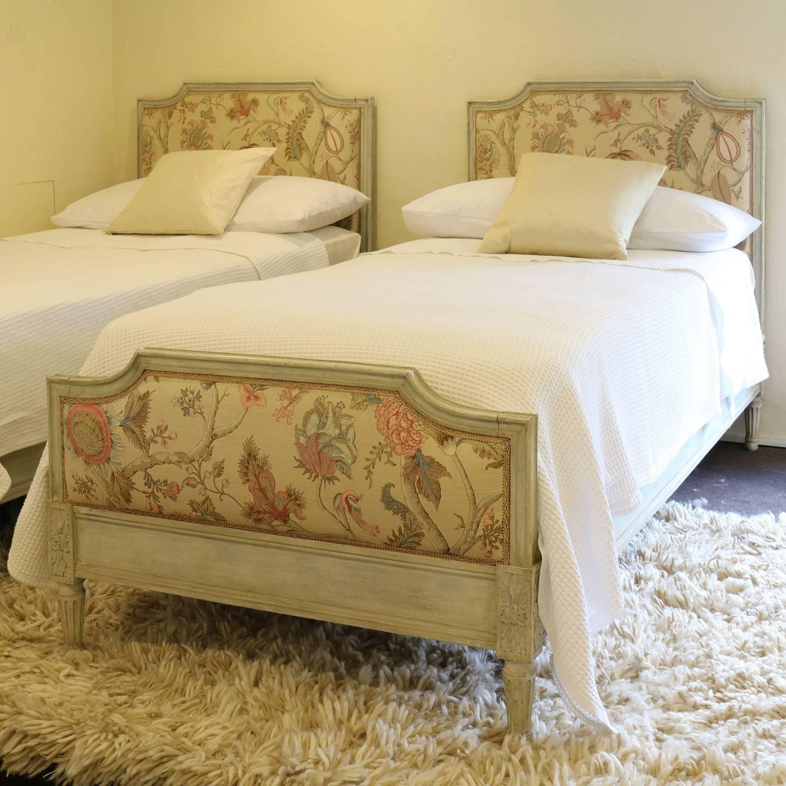 A matching pair of twin upholstered French beds in the Louis XVI style with distressed painted frames and attractive linen upholstered panels.

These beds accept 36 inch x 74 inch bases and mattresses, which can be supplied by Seventh