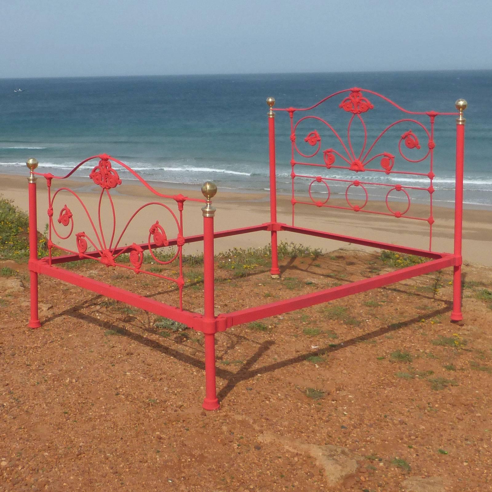 A cast iron bedstead from the mid-Victorian era with decorative castings and brass knobs and collars.

This bed is currently painted in red. It can be restored in any color you wish, including the favourites of black, cream or white.

This bed