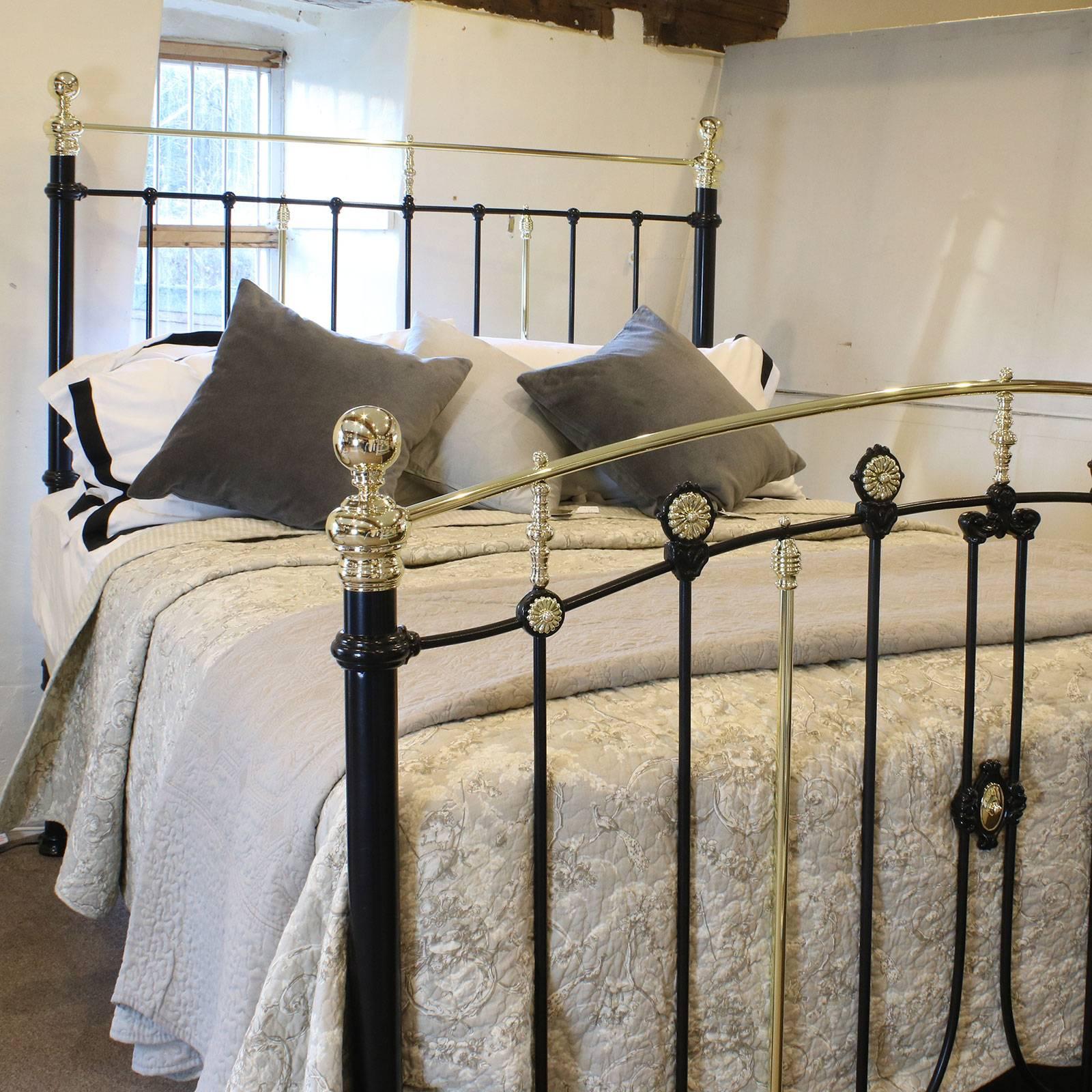 A decorative brass and iron bed in black with arched top rail on footboard and brass rosette decoration, adapted from an original Victorian frame, circa 1895.

This bed accepts a British king-size or American queen-size (60 inches, 5ft or 150cm)
