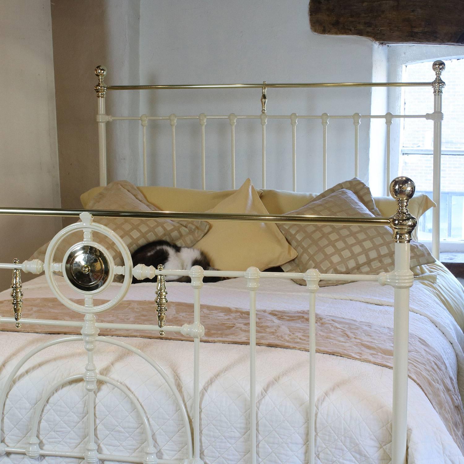 A decorative brass and iron bed in cream with ornate foot panel of central brass rosette and spindles, adapted from an original Victorian frame, circa 1895.

This bed accepts a British king-size or American queen-size (60 inches, 5ft or 150cm) base