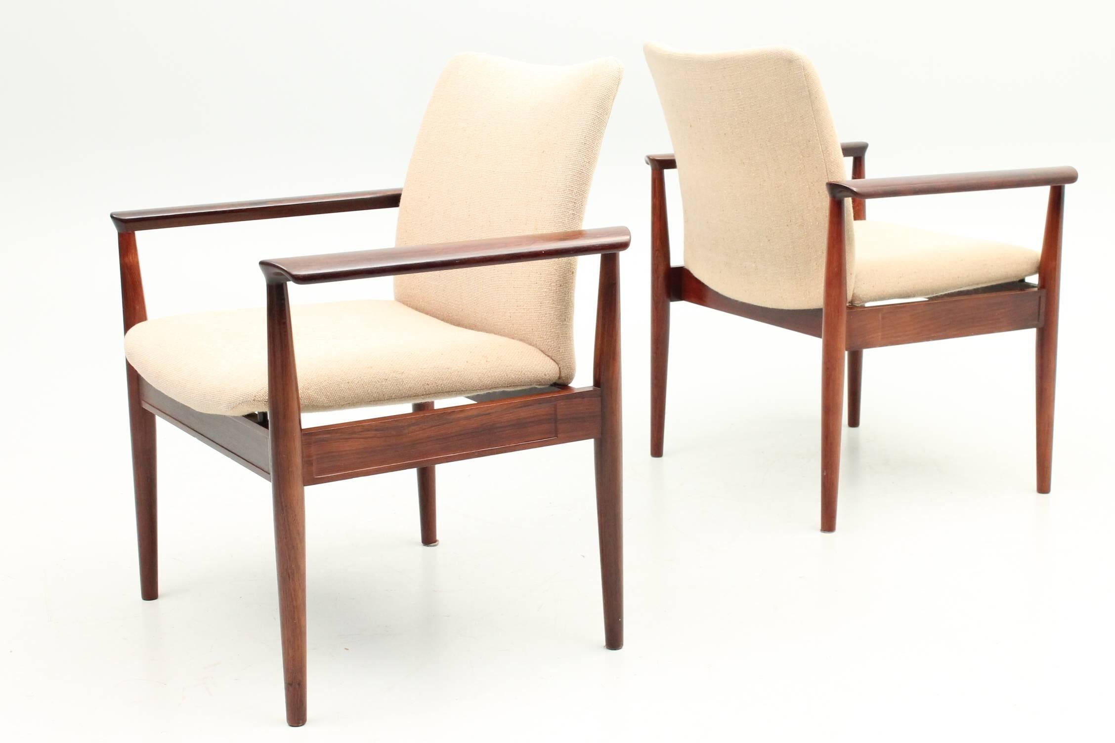 Beautiful set of four diplomat chairs designed by Finn Juhl for Cado. The cream upholstery perfectly contrasts the dark colored rosewood frame. These chairs are in excellent condition and still feature their original stamps and markings.
 