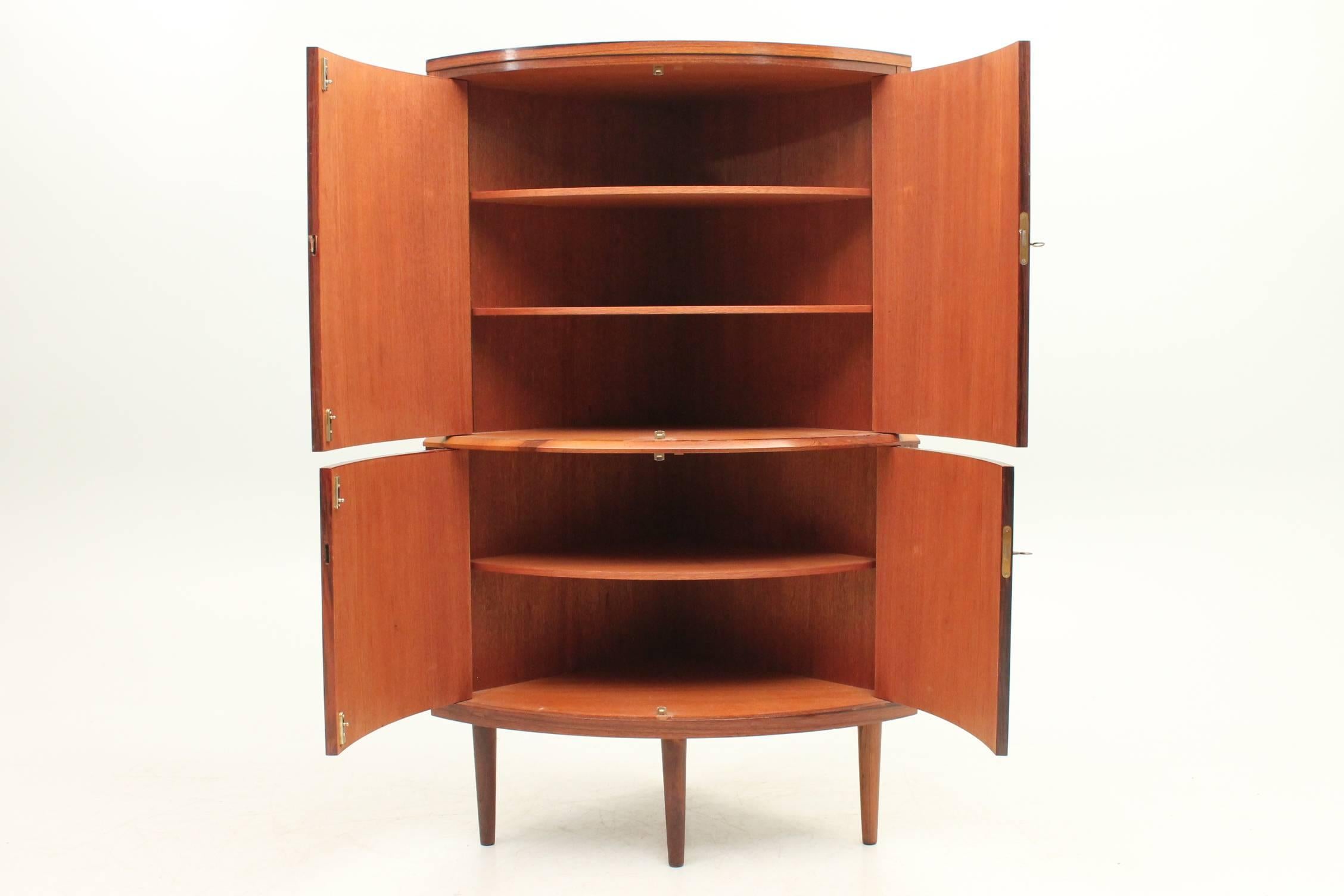 Beautiful rosewood corner cabinet. The front of this cabinet is rounded which makes it look even more unique. The wood features a thick, drastic grain and the shelves on the interior are fully adjustable to meet your storage needs. 