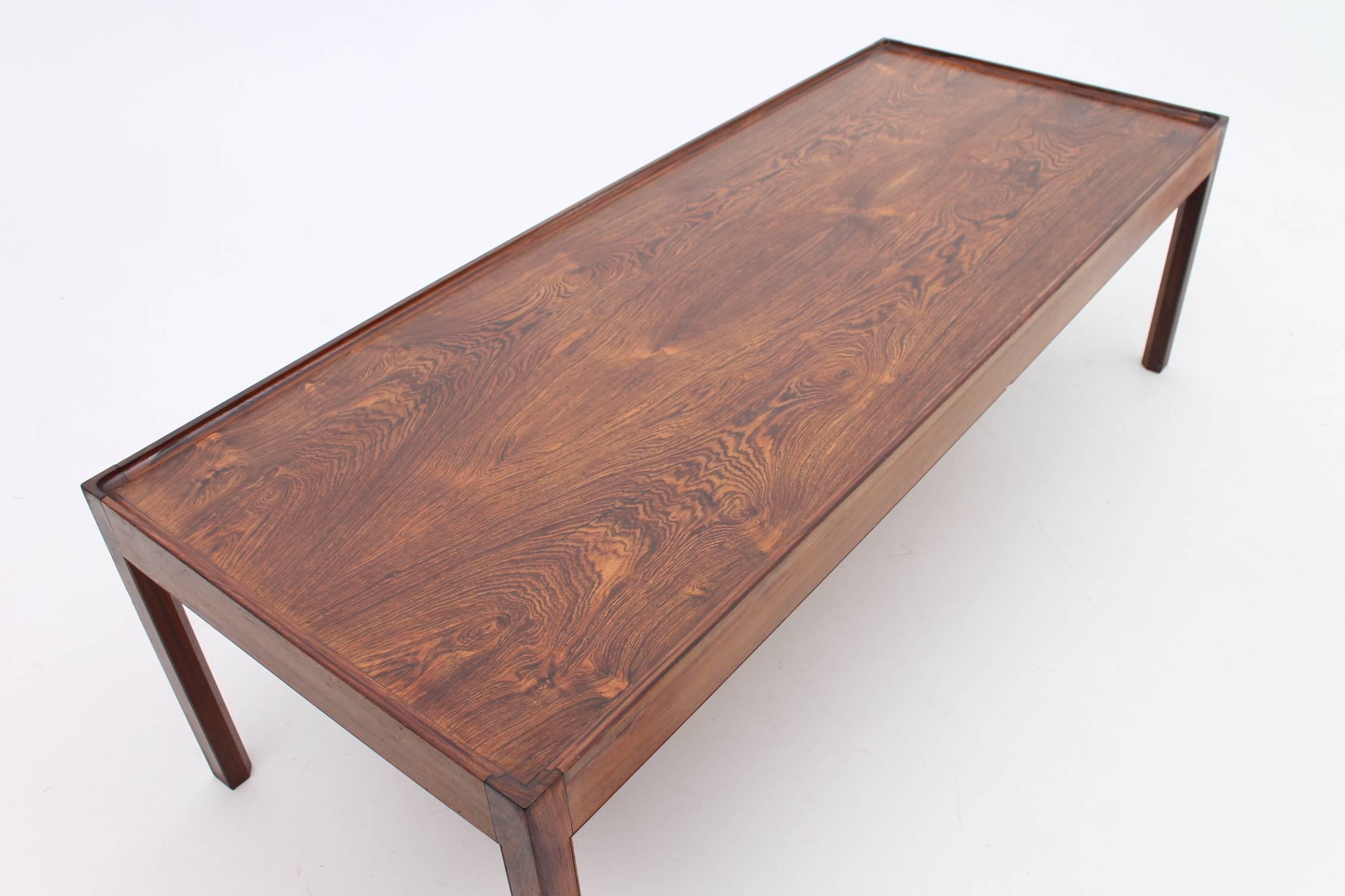 Rosewood coffee table designed and manufactured by an unknown designer. This table has a small “lip” around the edge of it, so you don’t have to worry about things rolling off of it. The functional yet beautiful design of this table makes it a huge