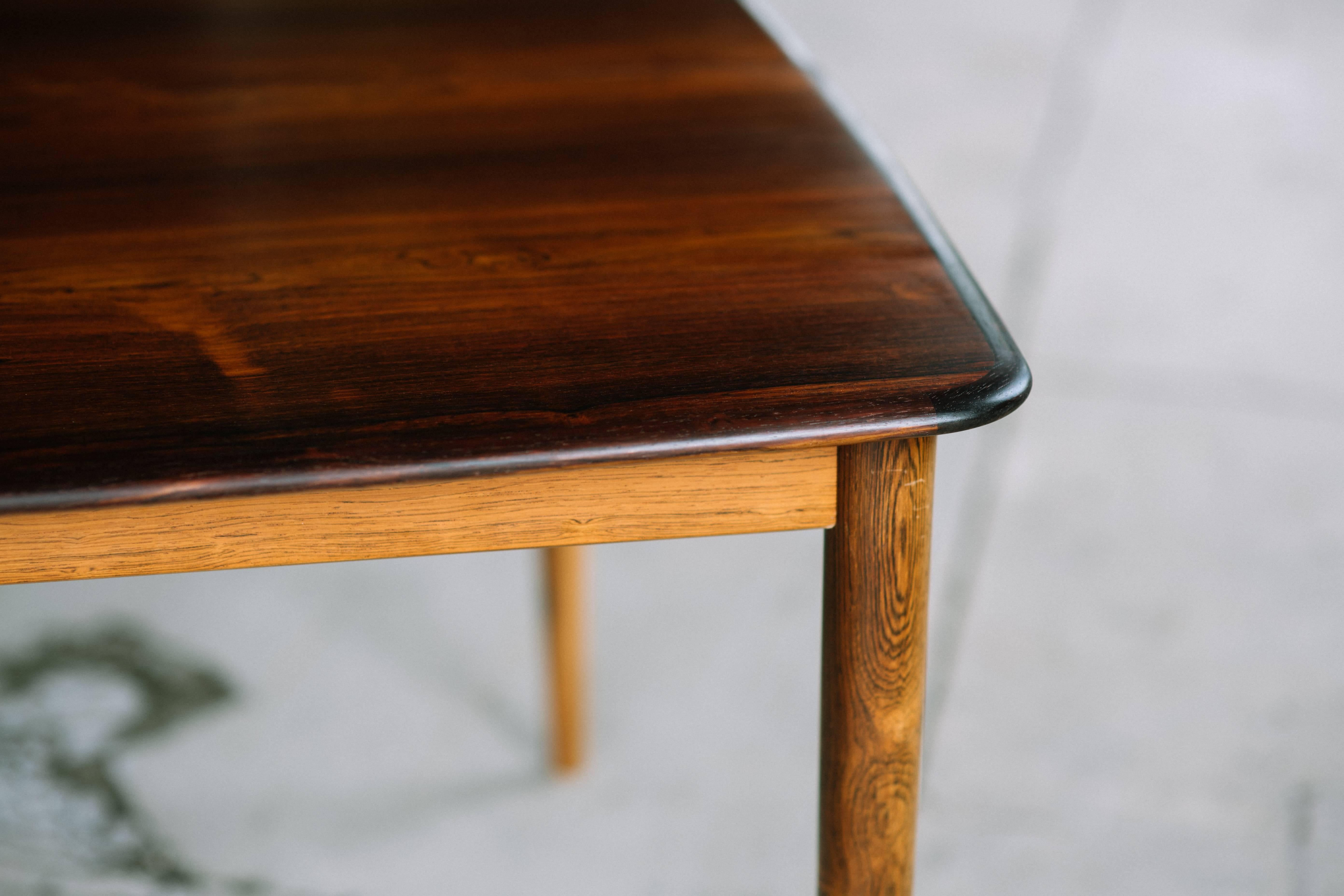Gorgeous and unique square dining table commissioned by Illums Bolighus. This rosewood table has been fully professionally restored and is in perfect condition. The legs / base of the table are slightly lighter than the top of the table. The leaves