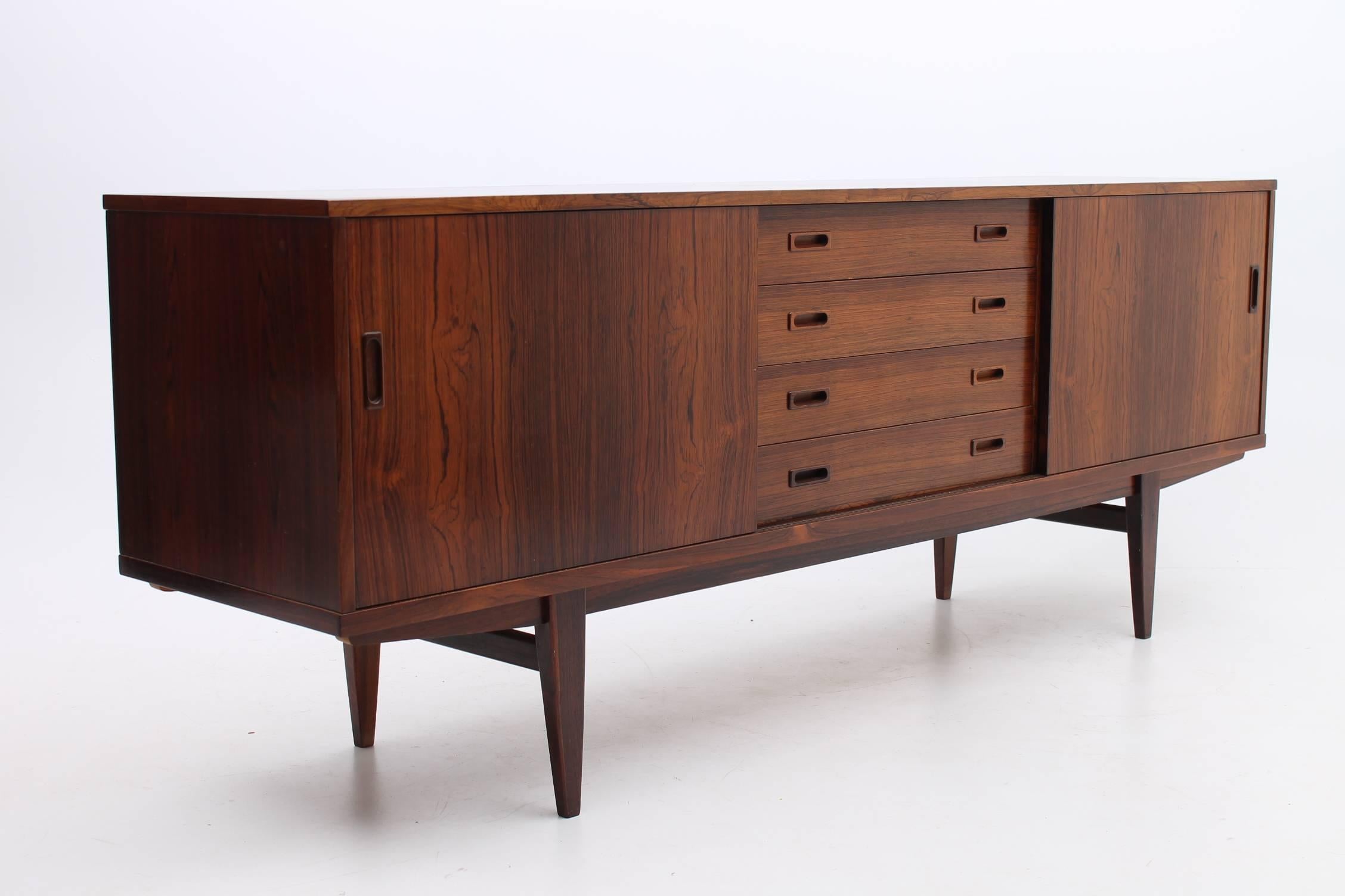 Beautiful rosewood credenza designed and manufactured by Lyby Mobler. This credenza has adjustable shelves on either sides and drawers in the middle. It also features handmade handles and the rosewood grain is thick wood grain. This credenza has