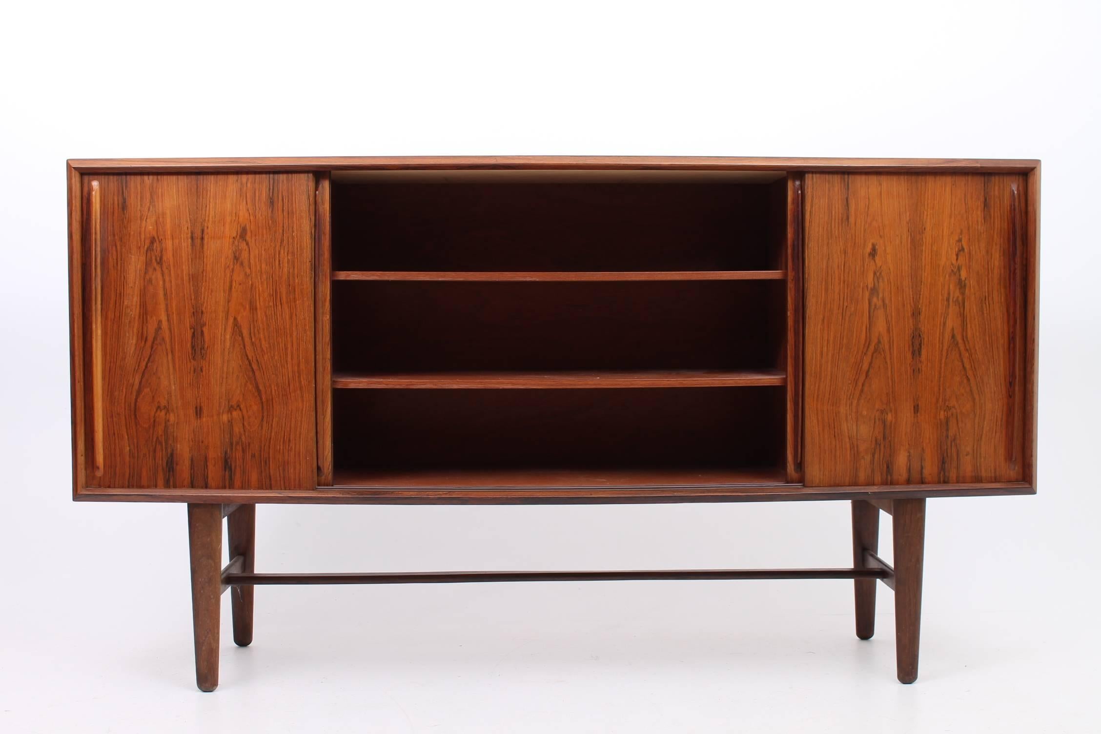 Gorgeous rosewood credenza designed by Henry Rosengren Hansen for Brande Møbler. The credenza has four opening doors - the middle section is larger with two adjustable shelves. The left side compartment has drawers and the right has more adjustable