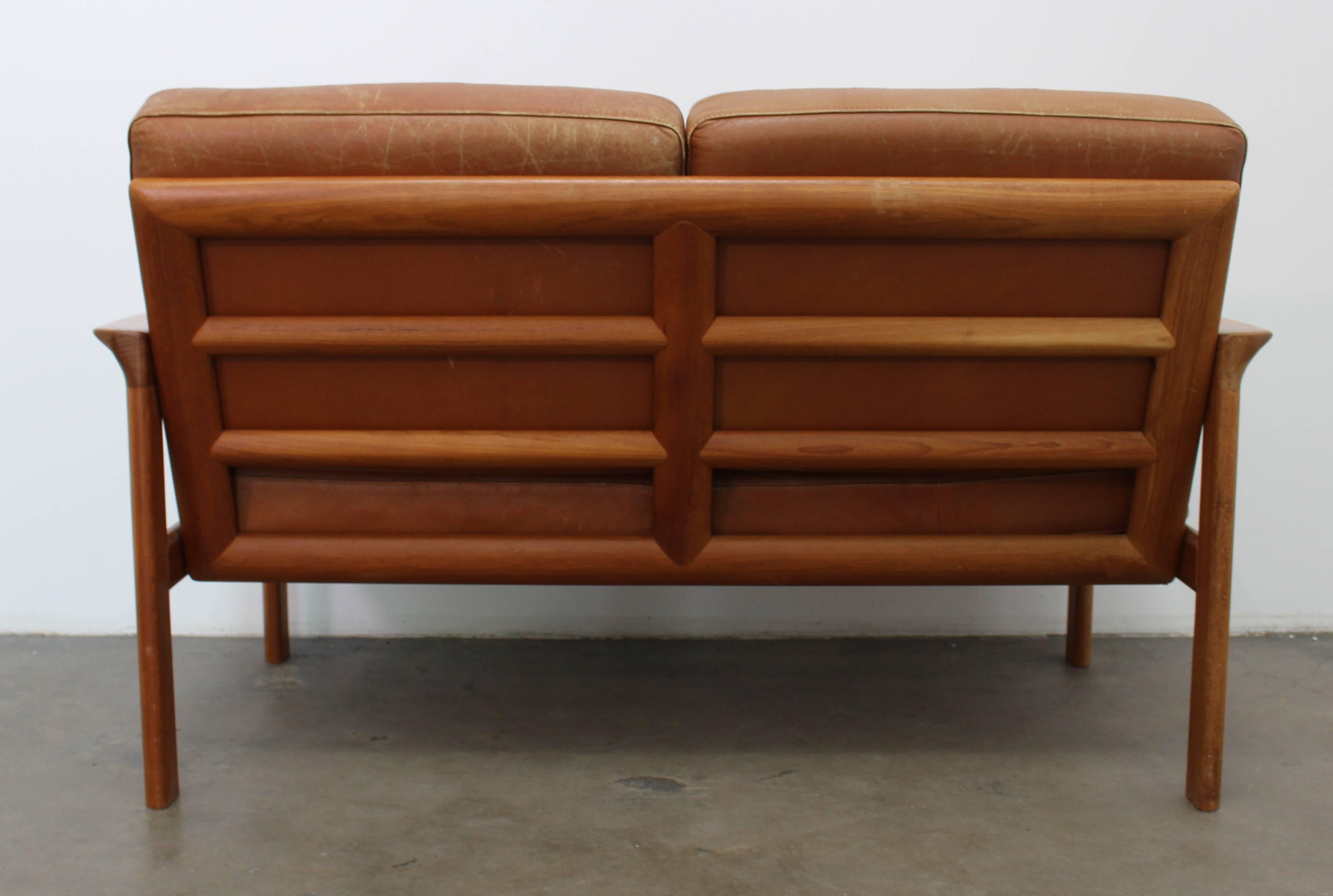 Beautiful cognac leather sofa (or loveseat!) with an open teak frame, circa 1970. The teak frame has been restored and is in good condition; the cushions are original and there is some patina on them (pictured.) This loveseat has an open back frame