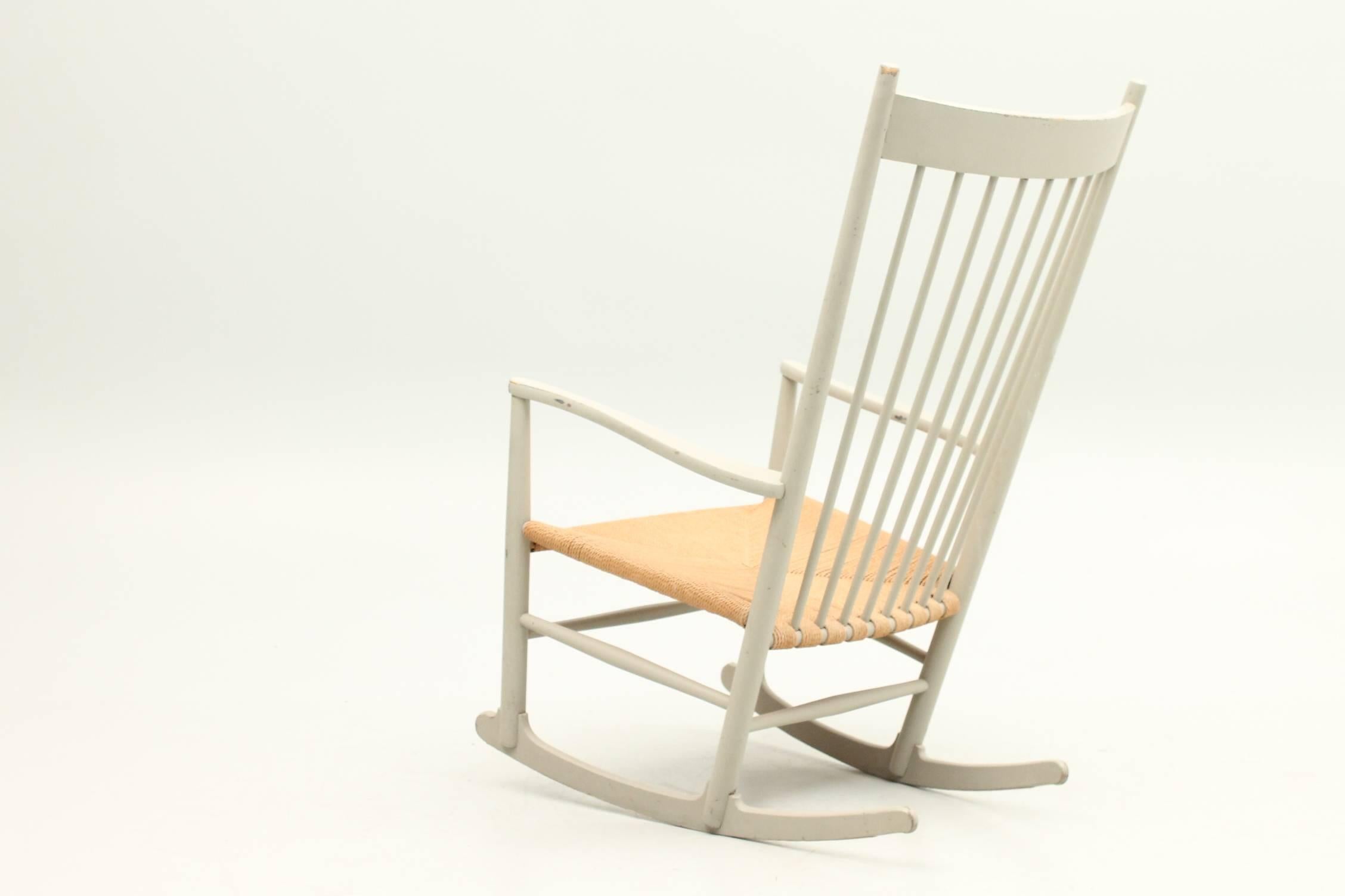 Beautiful model J16 rocking chair designed by Hans Wegner for FDB Møbler. The rocking chair is made of a beech frame that has been painted a beautiful light gray color. The seat is made of wicker and the seat is in excellent condition. The chair has