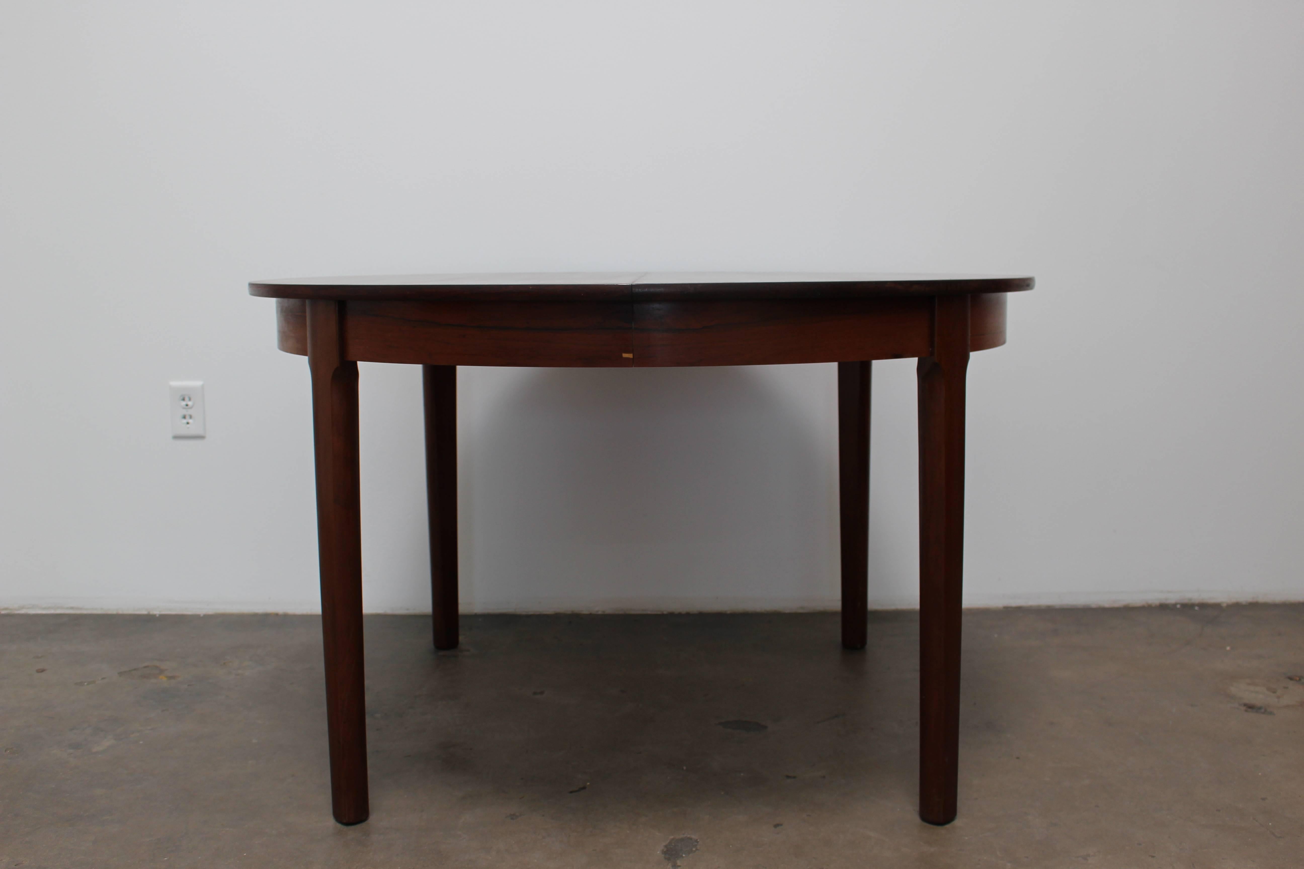 Round rosewood dining table made in the 1950s. The beautiful, simple design of this table is extremely versatile and can transition into any style of home. The rosewood is in good condition, with one chip on the skirt. The grain of the table is