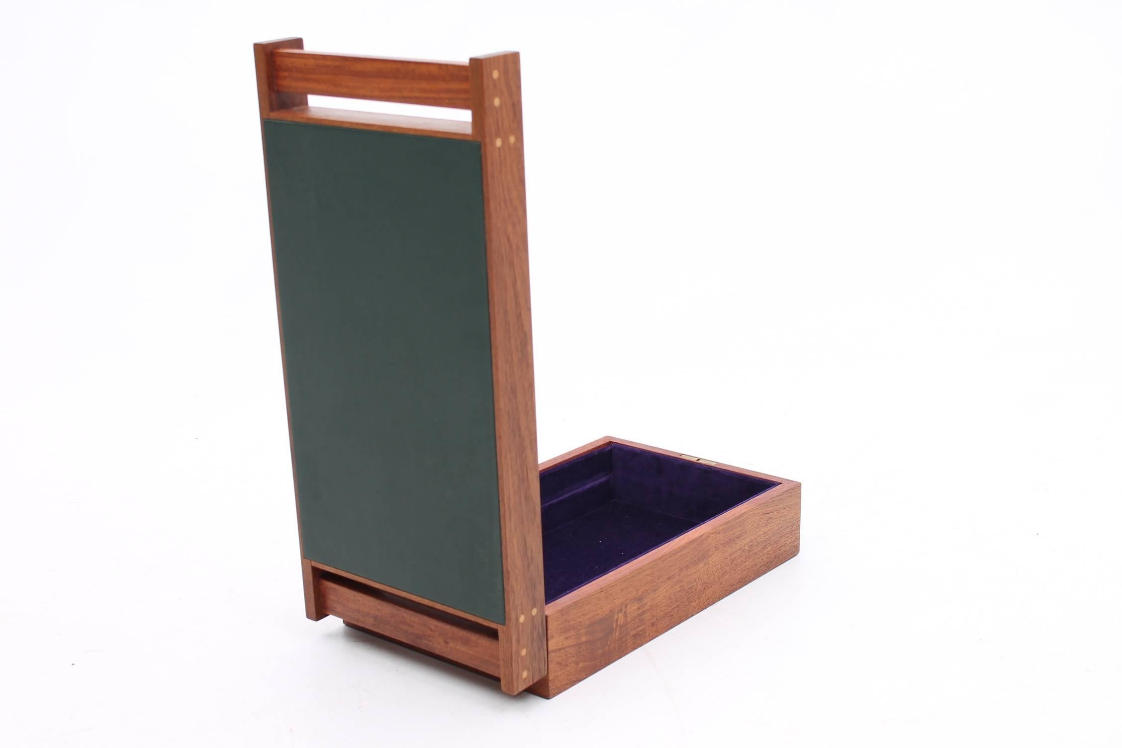 Stunning and unique jewelry box designed by Aksel Kjersgaard and produced by Odder Furniture. The gorgeous rectangular box has teakwood with black leather on the top. The interior of the box has a mirror and velvet lining.