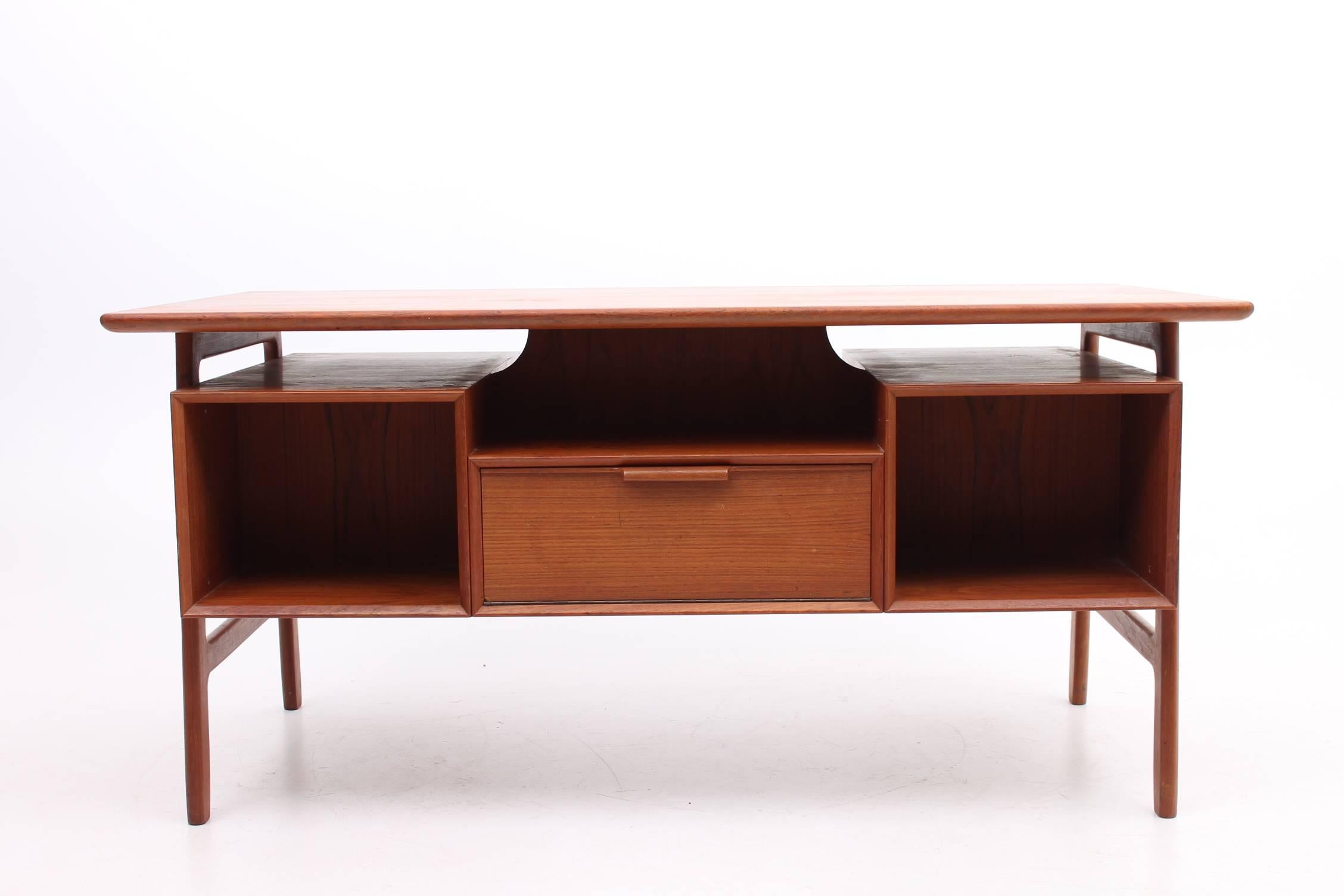 Beautiful desk made of teak designed by Gunni Omann for Omann Jun Møbelfabrik. This desk is from the model 75 series. The desk features a desk top that floats over the base. The base has three drawers on either side of the chair opening and open
