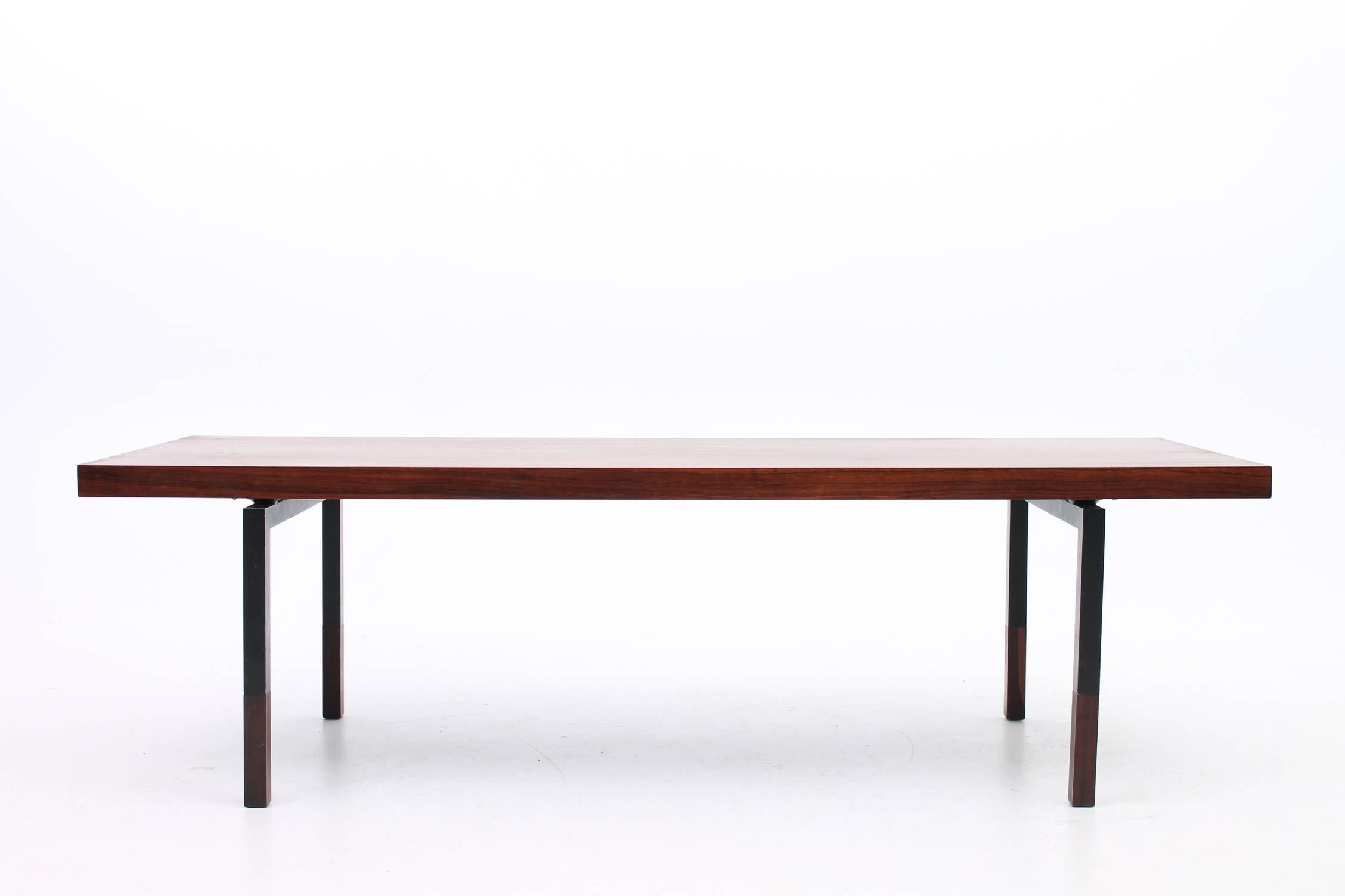 Minimalist coffee table made of rosewood designed by HW Klein for Bramin Møbler. This gorgeous coffee table has a solid rosewood top with a dark, beautiful grain. The tabletop floats above black steel legs with more rosewood detail at the feet. This