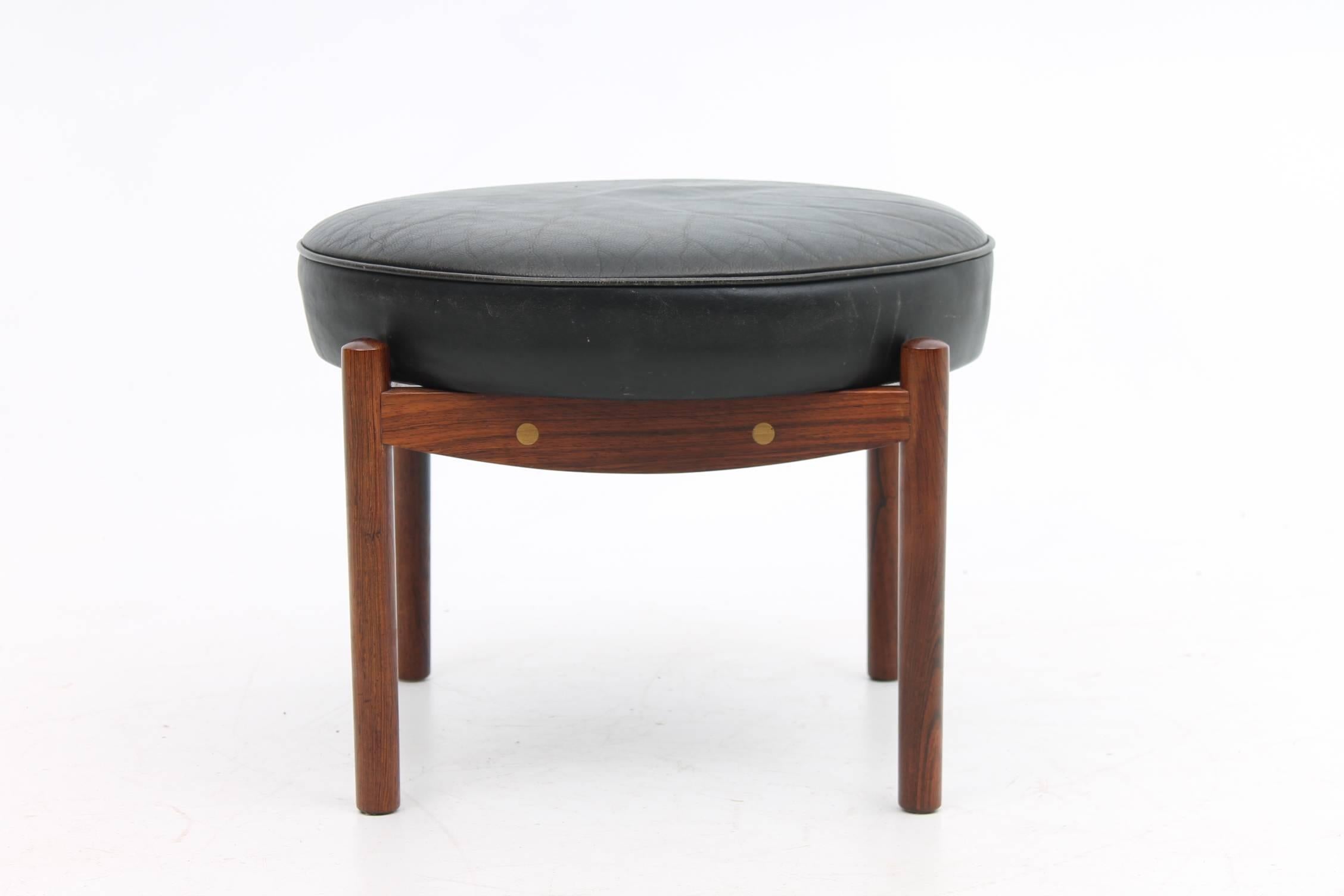 Beautiful footstool made of a rosewood frame with a circular leather cushion. The rosewood frame has a brass detail that can be seen from the side as an extra detail. The circular cushion fits perfectly in the square wooden frame.