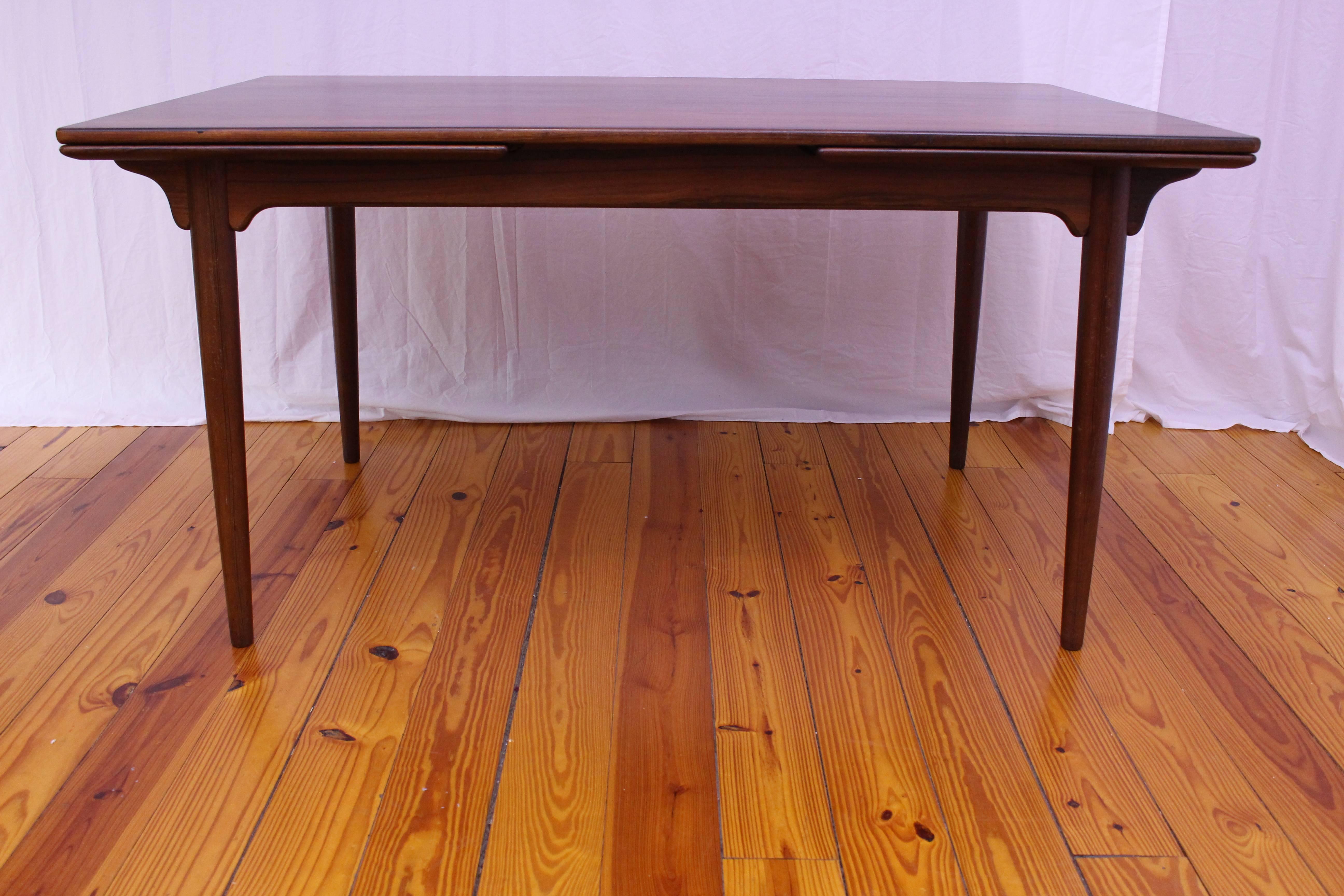 Beautiful rosewood rectangular table by Gunni Omann for Omann Jun. This table features two large pull-out leaves that self store underneath the top of the table. When the leaves are fully extended, the table length measures 100 inches. The dark,