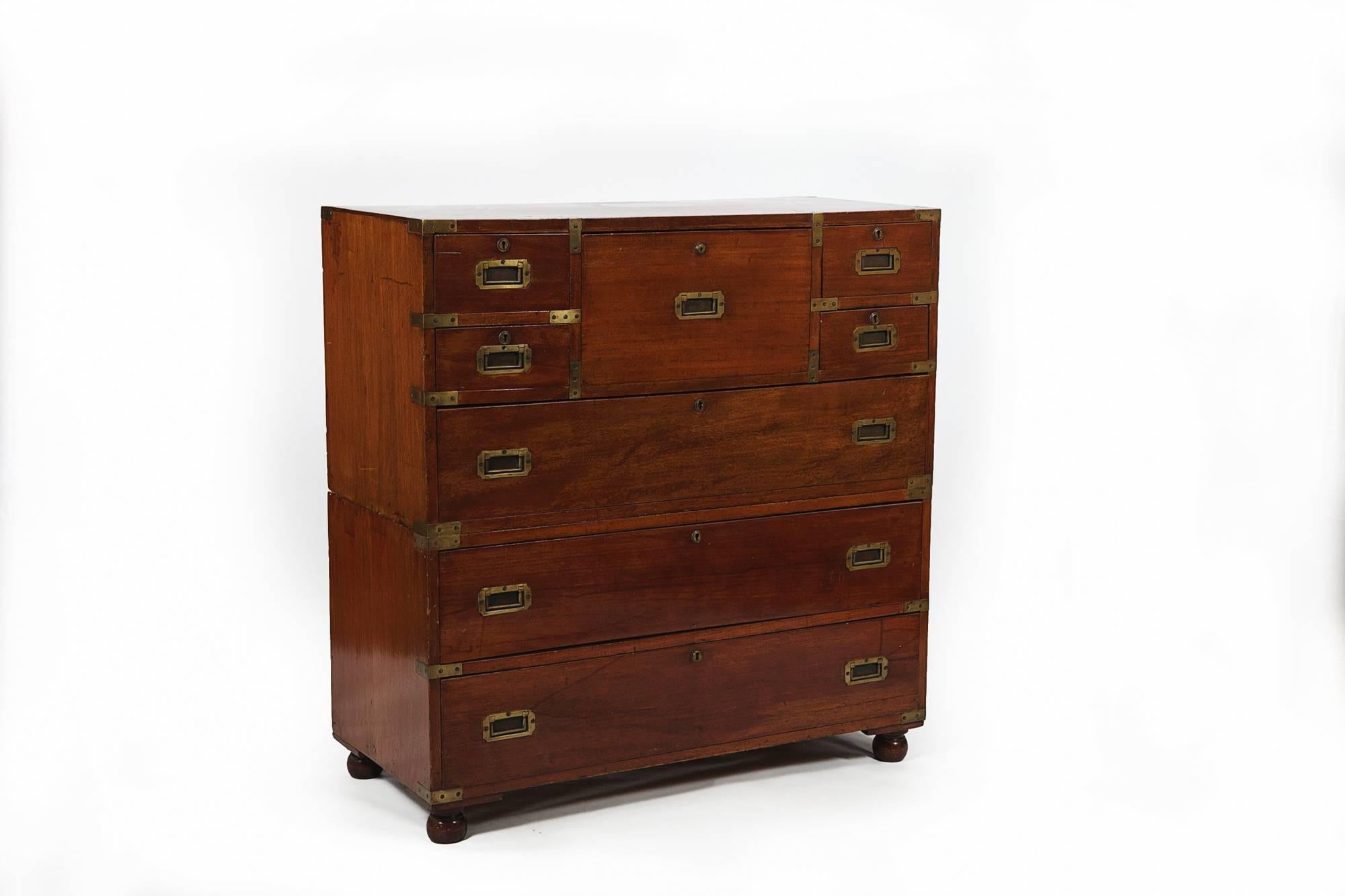 19th Century mahogany military campaign chest with miniature fall front secretaire opening to reveal fitted compartments of scriver and pigeonholes flanked with four small drawers raised over three long drawers with brass pulls terminating on bun