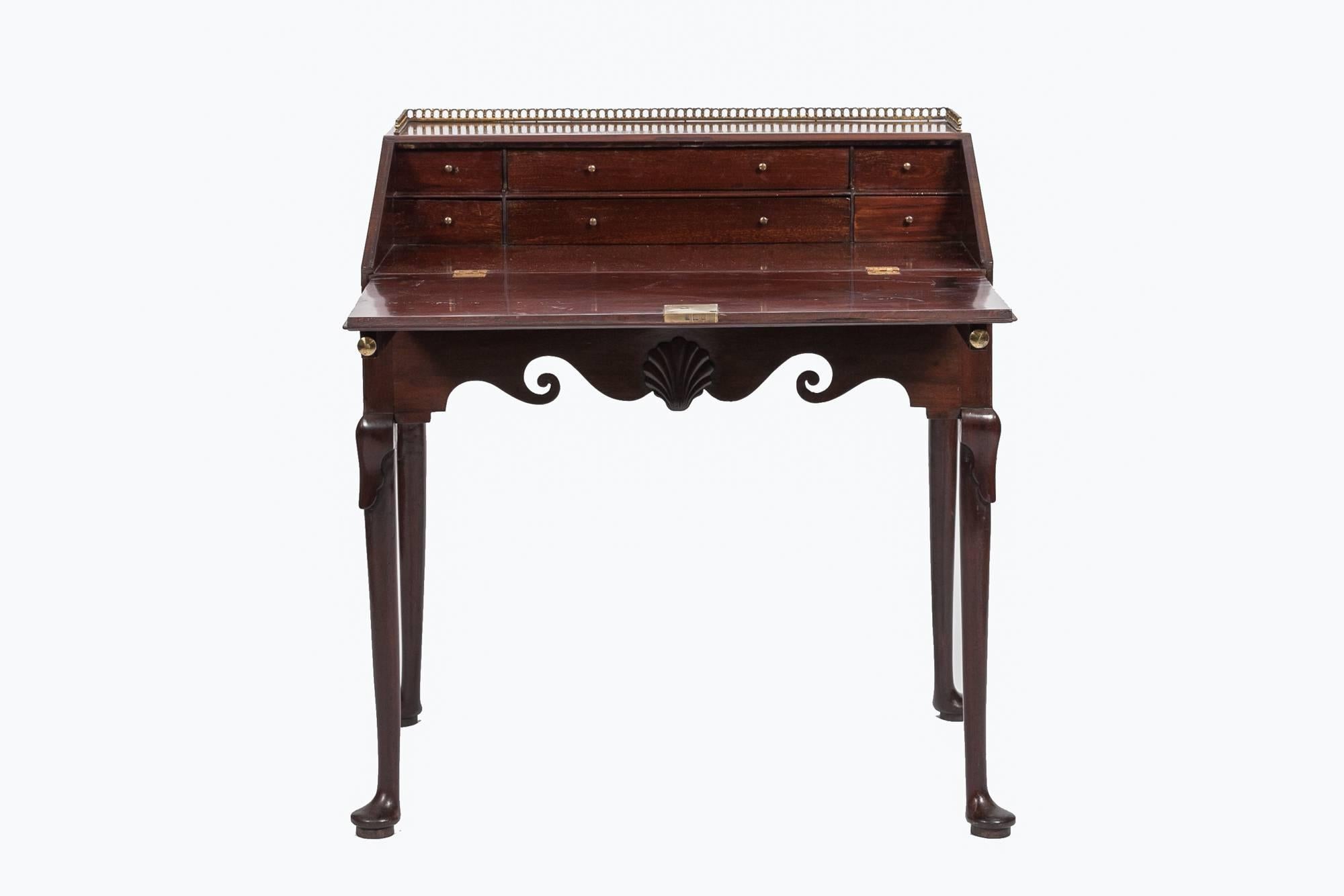 18th Century George II mahogany ladies writing bureau topped by brass pierced gallery.  The sloped fall front enclosing six drawers above a shaped frieze incorporating scrolls flanking a central scallop shell above stylised acanthus embellished