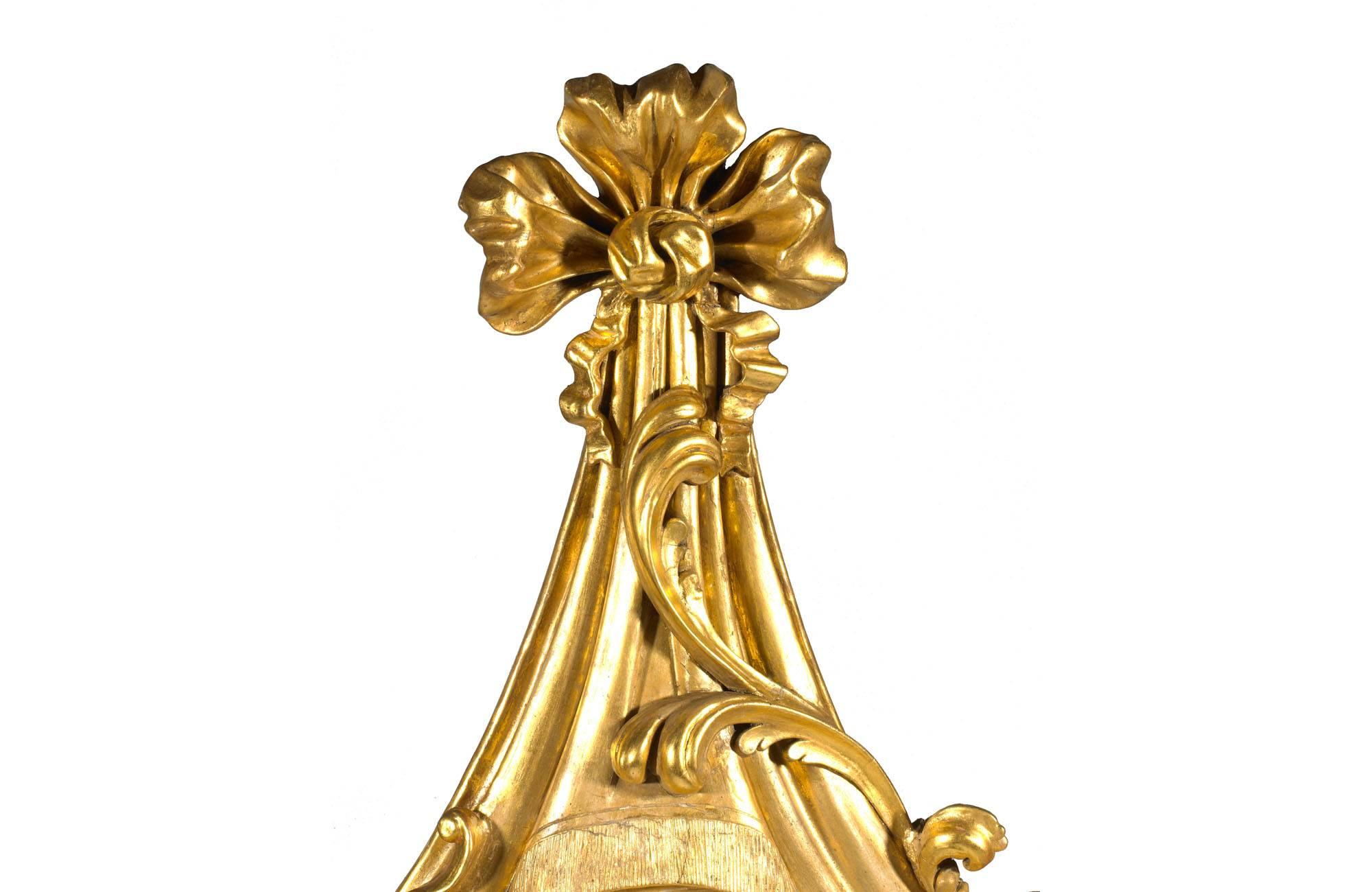 miroir convexe en bois doré du 19e siècle avec sculpture asymétrique. La partie convexe est ornée de godrons et de bourrelets, et est surmontée d'une draperie en bois doré feuillagé et sculpté d'un côté et d'une volute de l'autre. Le tablier est