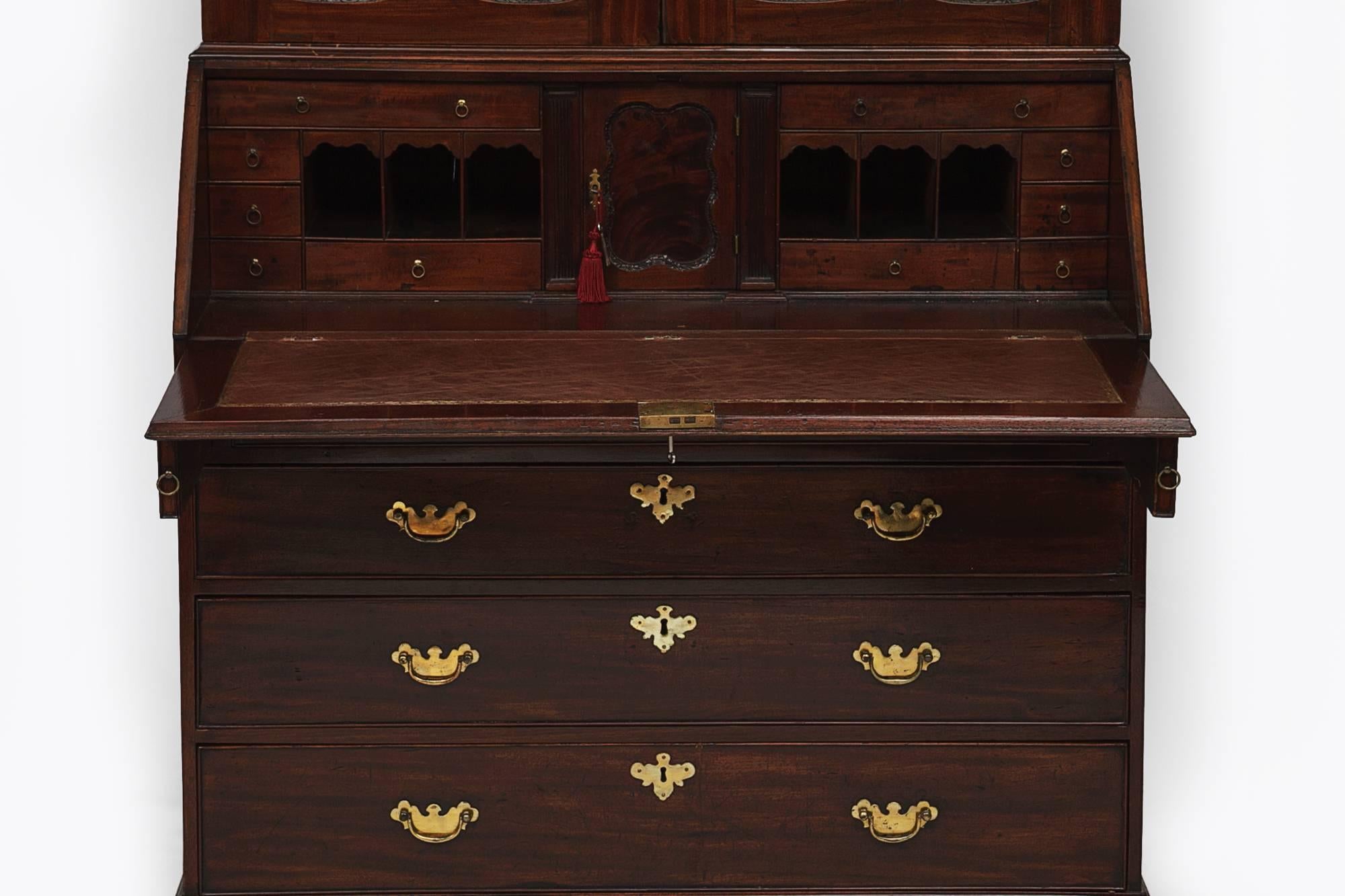 18th century George II Bureau bookcase with mirrored doors. The stepped cornice above two mirrored doors opening to reveal shelving above slope front secretaire with fitted interior, above four graduated brass handle drawers.
