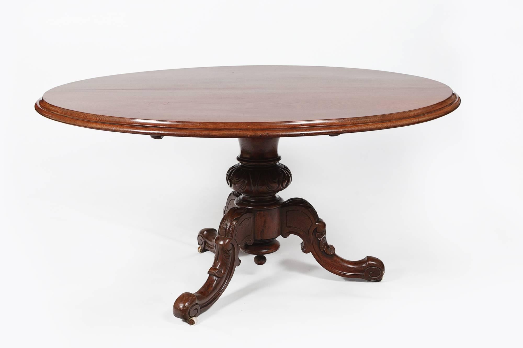 table à dîner ovale Regency du XIXe siècle, en acajou, à plateau basculant. Sur une seule cosse, avec trois pieds sculptés évasés sur des roulettes en laiton.