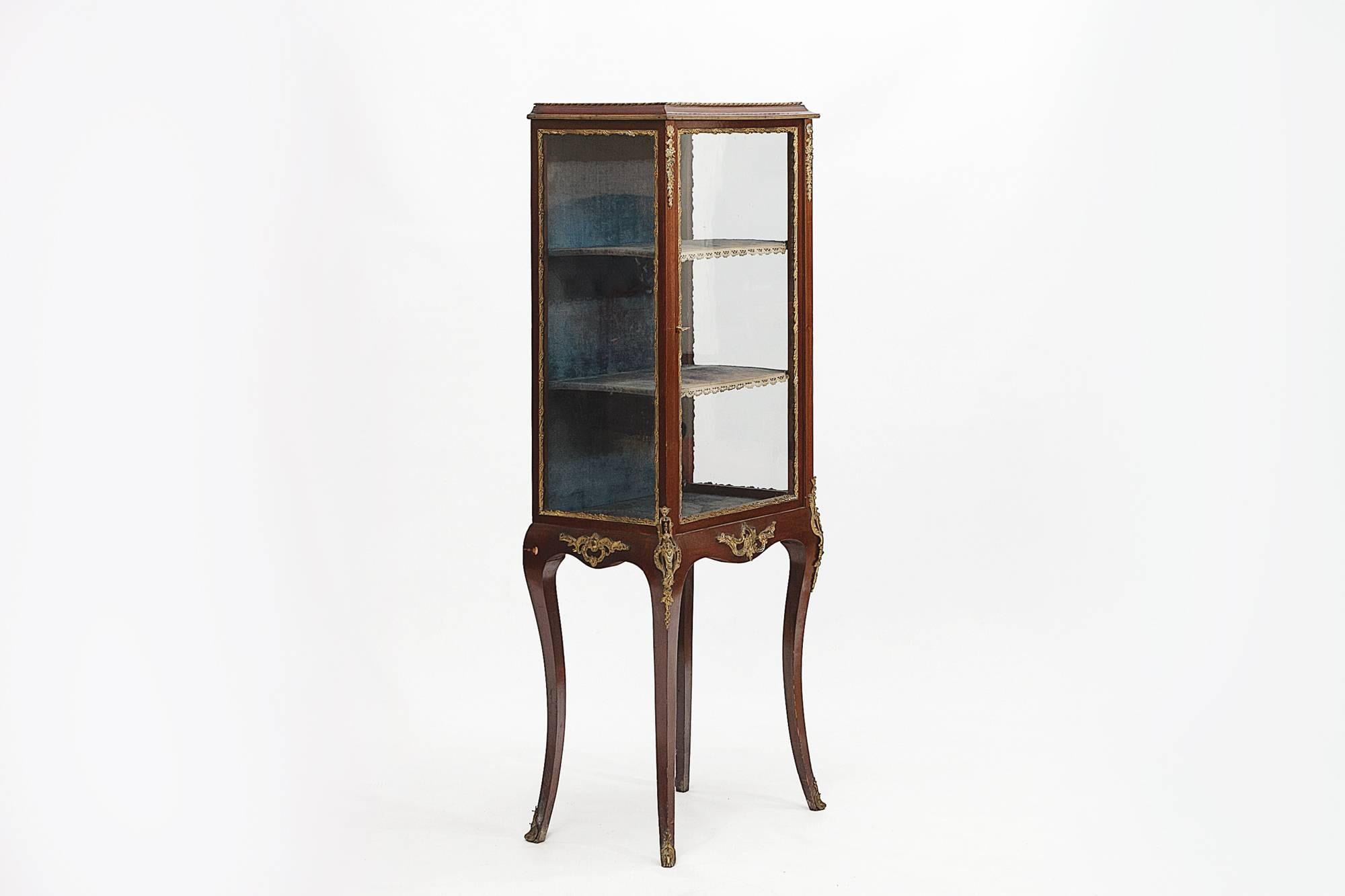 19th century Regency French style mahogany vitrine with brass mounts, the cabinet with two shelves, the interior lined with velvet supported on sabre legs.